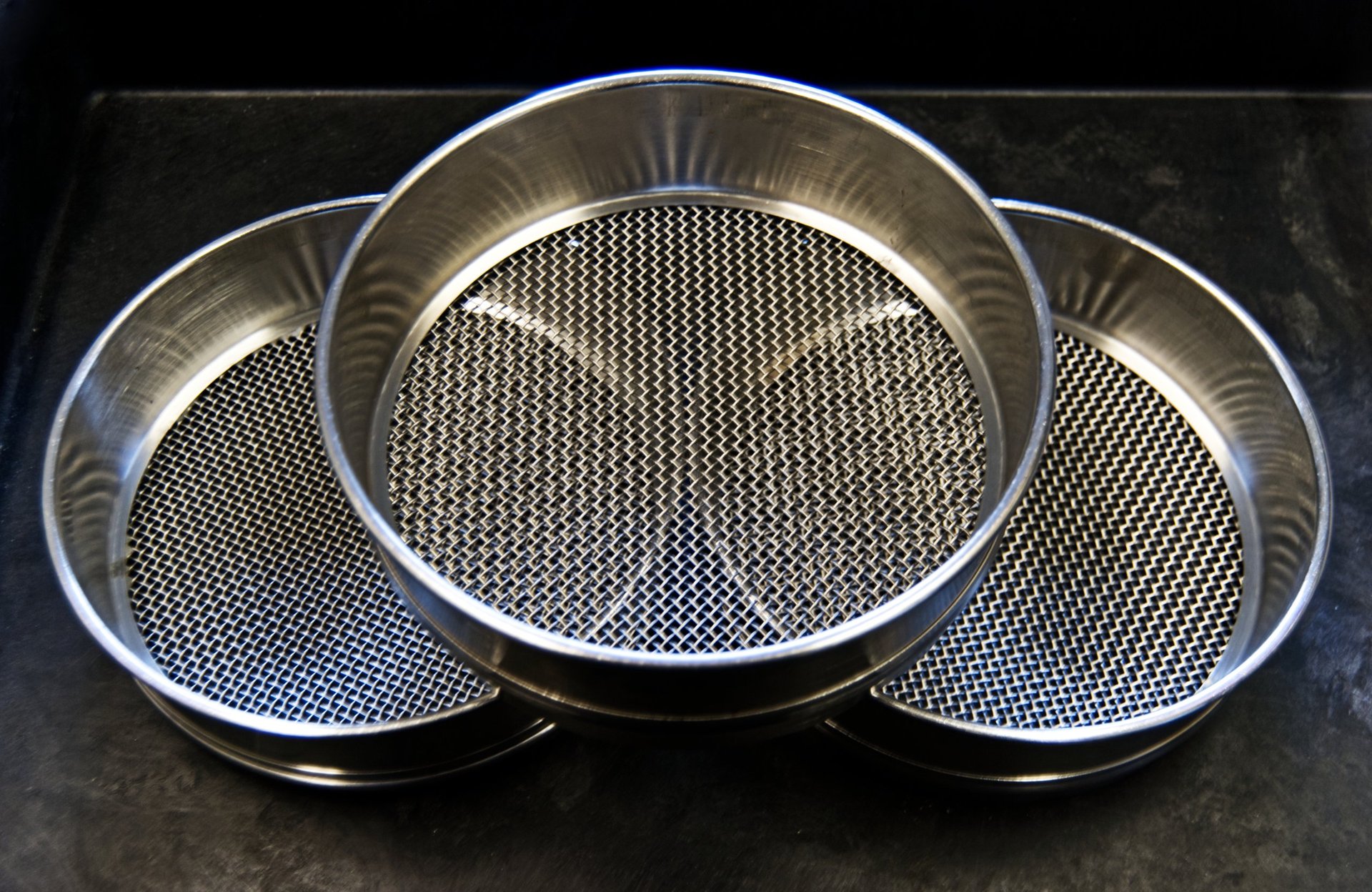 Steel sieving mesh of the kind used to establish the size fractions a charge is divided into.