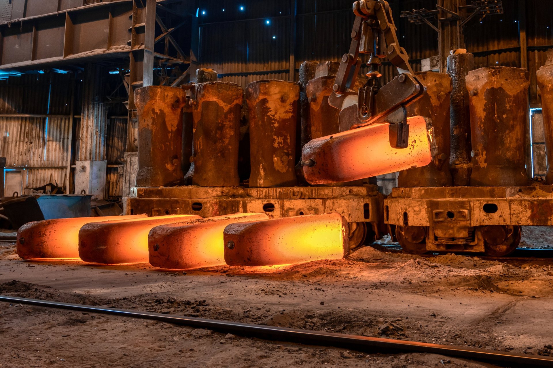 Red-hot steel billet being forged into rolled metal at a mill