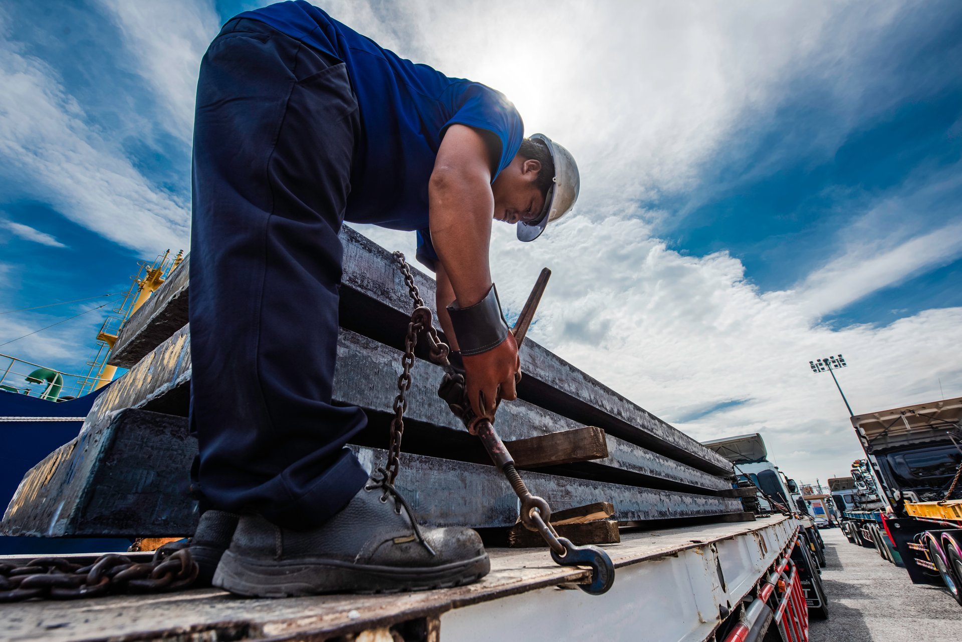Coil and slab cargo being lashed and secured on a truck trailer before transport