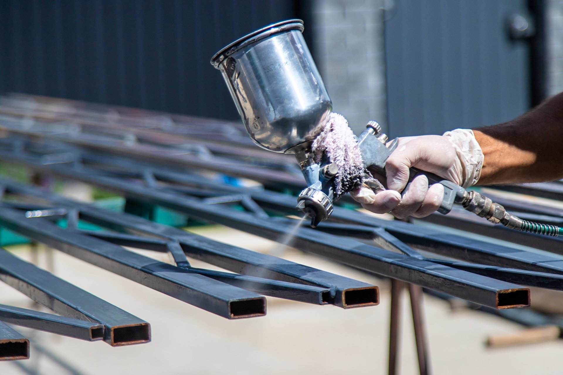Operator applying a finish to metal components in a controlled spray booth