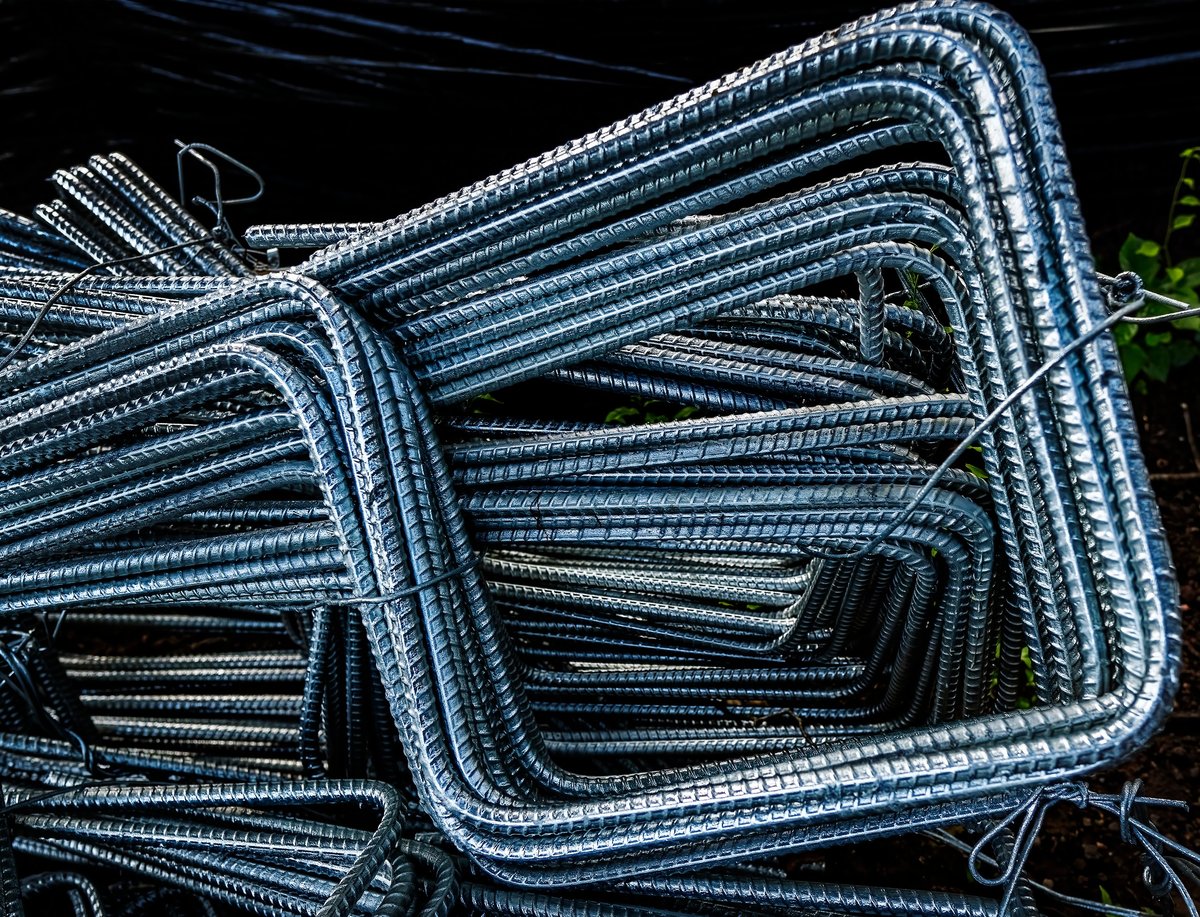 Bundles of reinforcing bar bent at right angles and stacked at a fabrication yard, showing the bend detail that must be checked against the permitted minimum diameter.