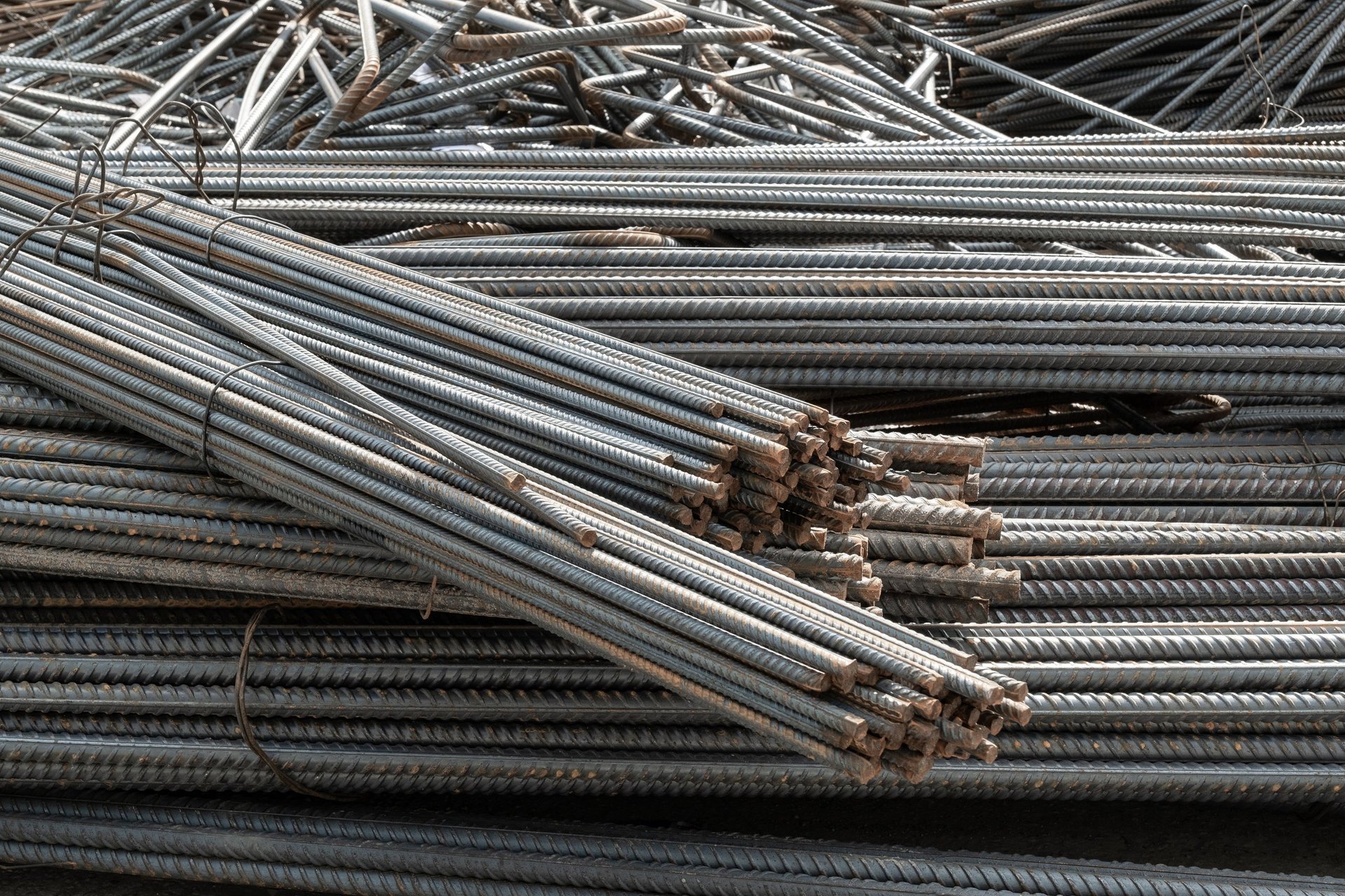 Galvanized rebar — a freshly coated reinforcing bar drawn from a zinc bath, with a coarse spangled coating surface visible along its length.