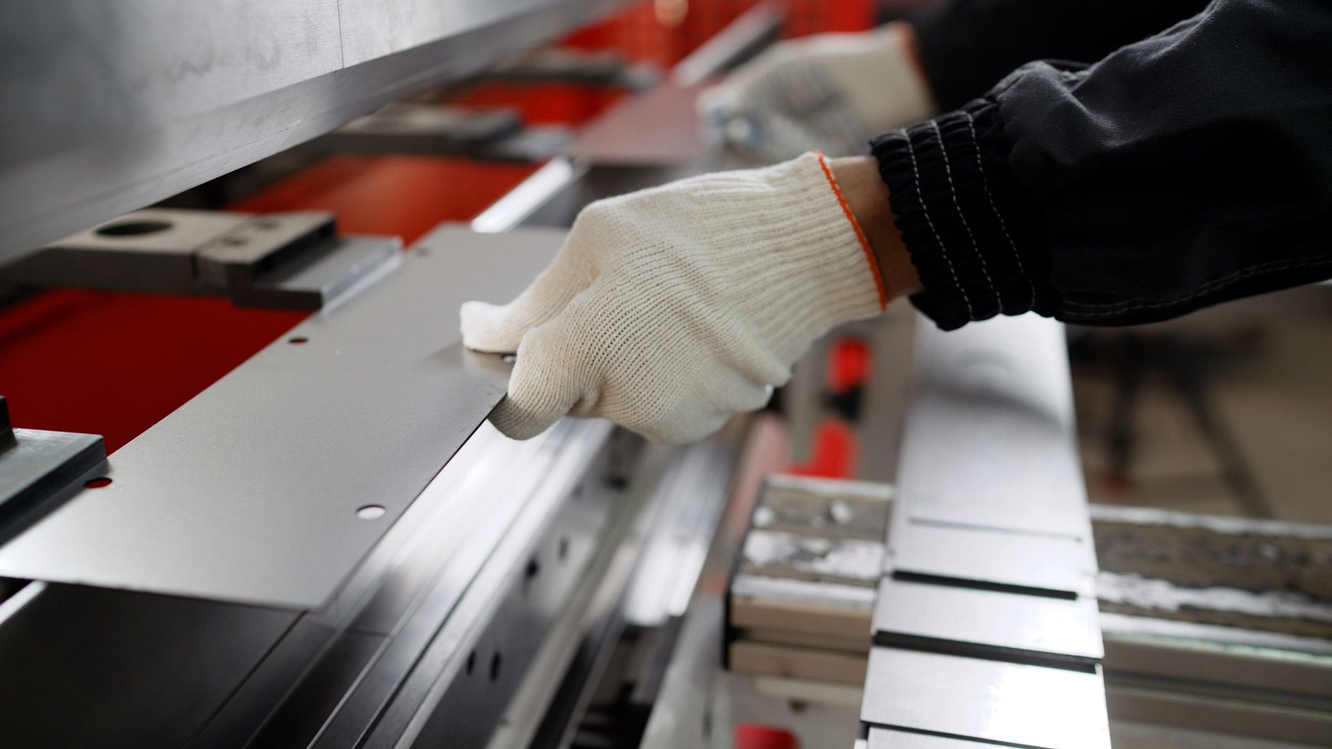 Worker forming sheet metal on a bending machine in a fabrication workshop