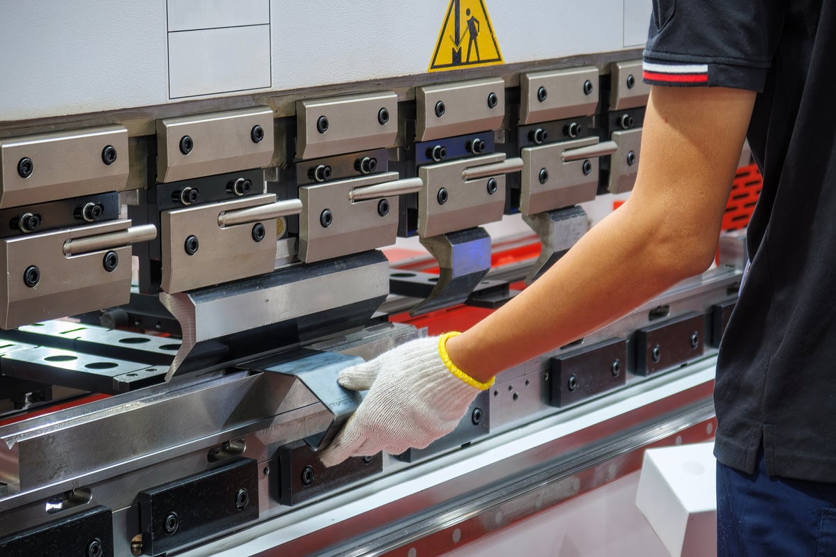 Operator forming steel sheet on a press brake — fabrication duty that shapes material family choice