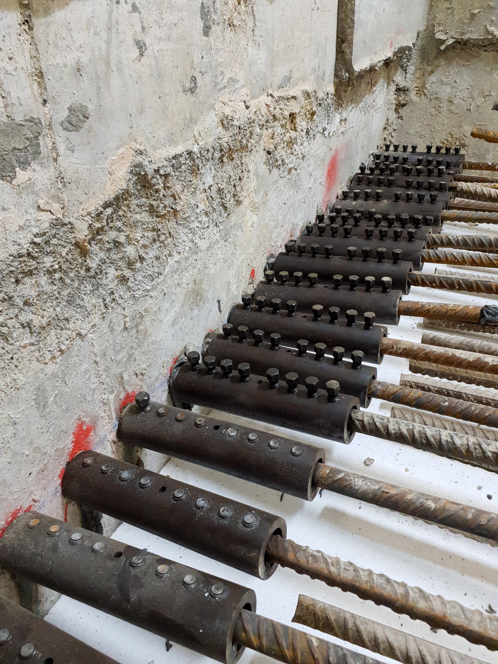 Close-up of a steel mechanical coupling system used to join reinforcing bar for load transfer, illustrating a connection method that must be specified by the design.