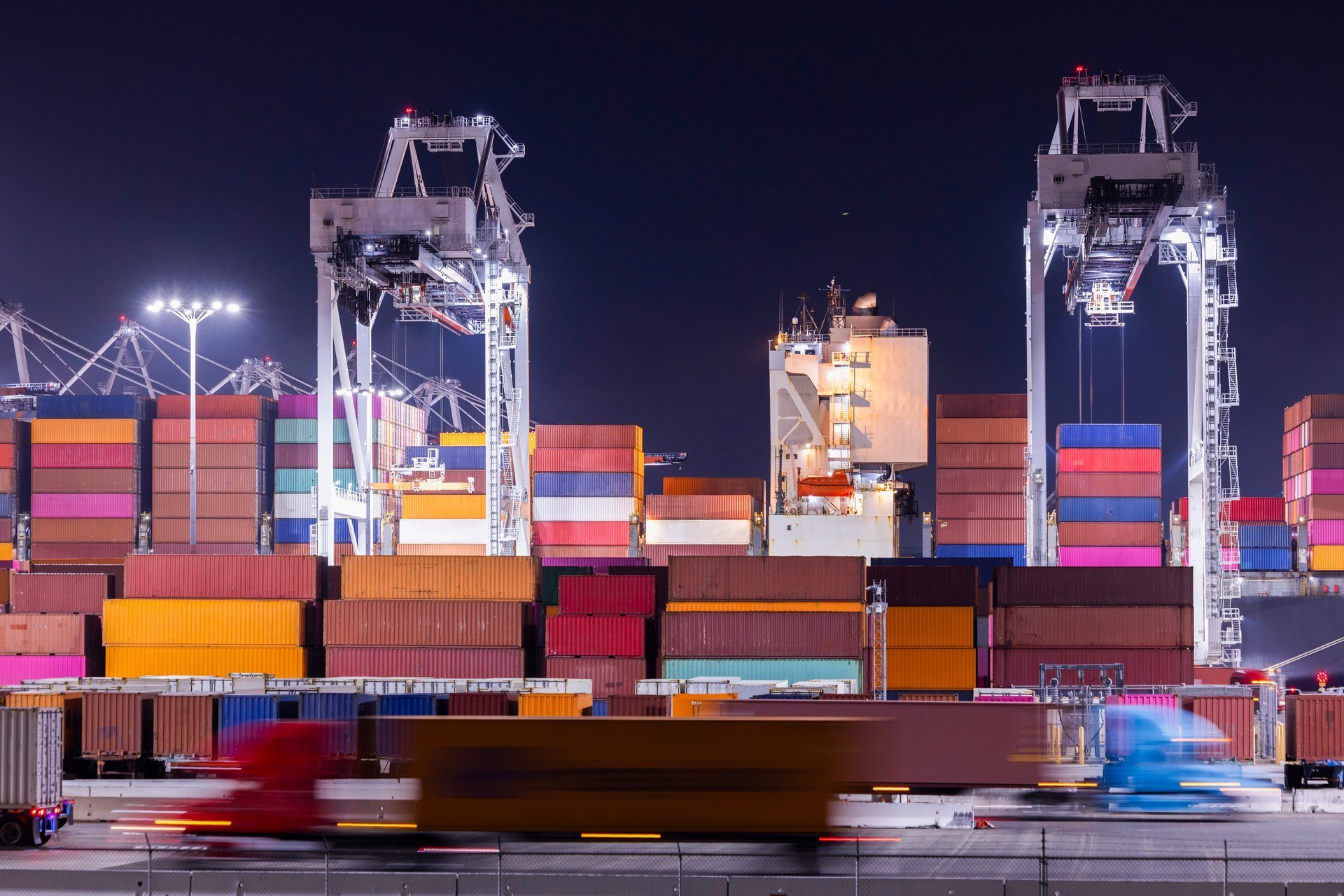 Container cranes loading a vessel at an industrial port, representing export consignment handling