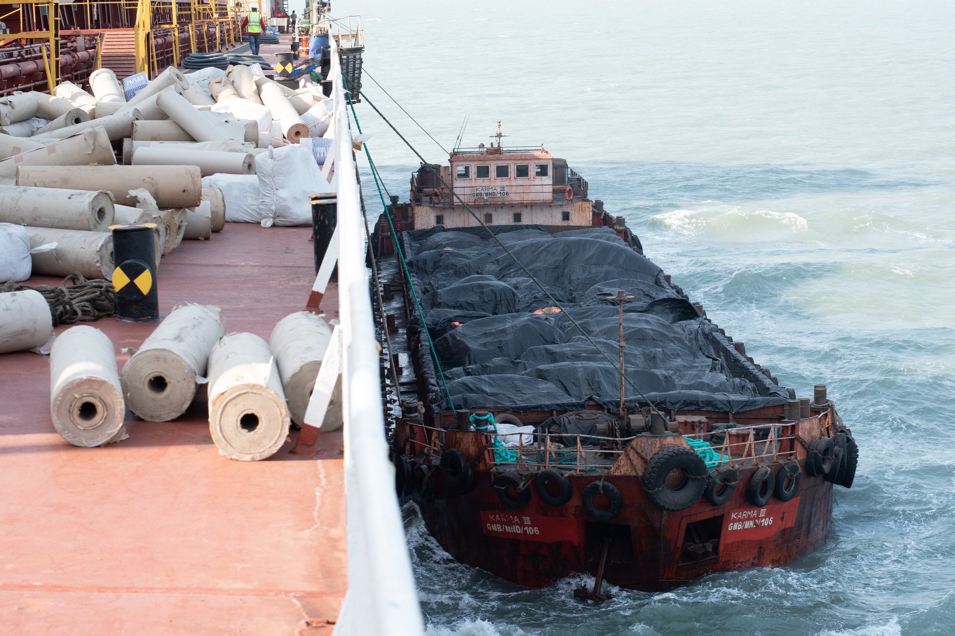 Commercial port staging area with bundled steel billets on dunnage awaiting customs-controlled release, with no company branding.