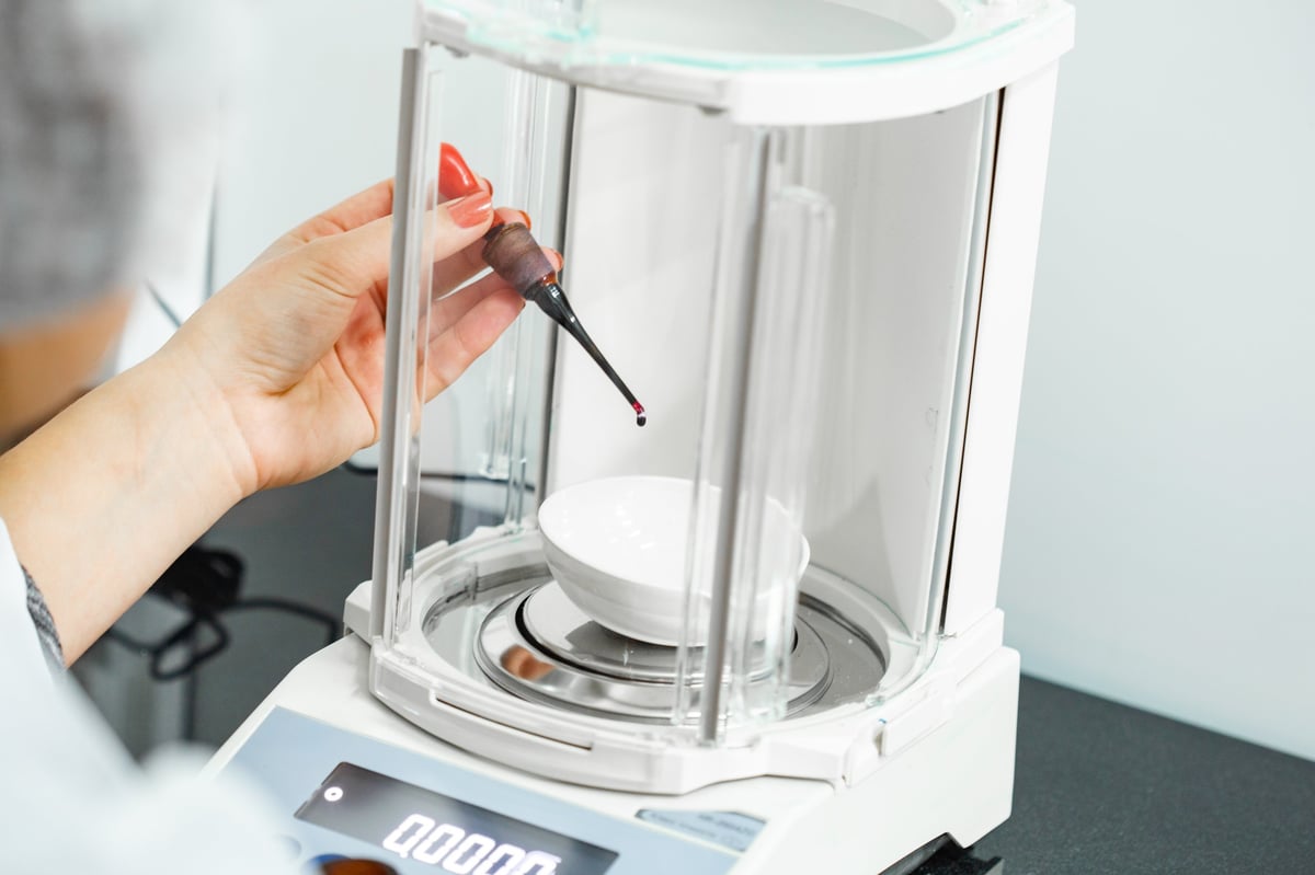 Laboratory analyst weighing a sample on an analytical balance during sample preparation