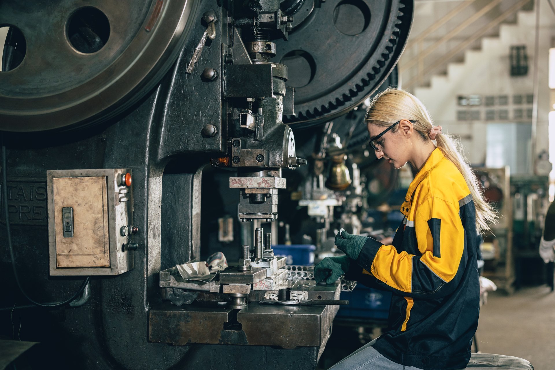 Operator stamping steel sheet at a press in a heavy metalworking factory