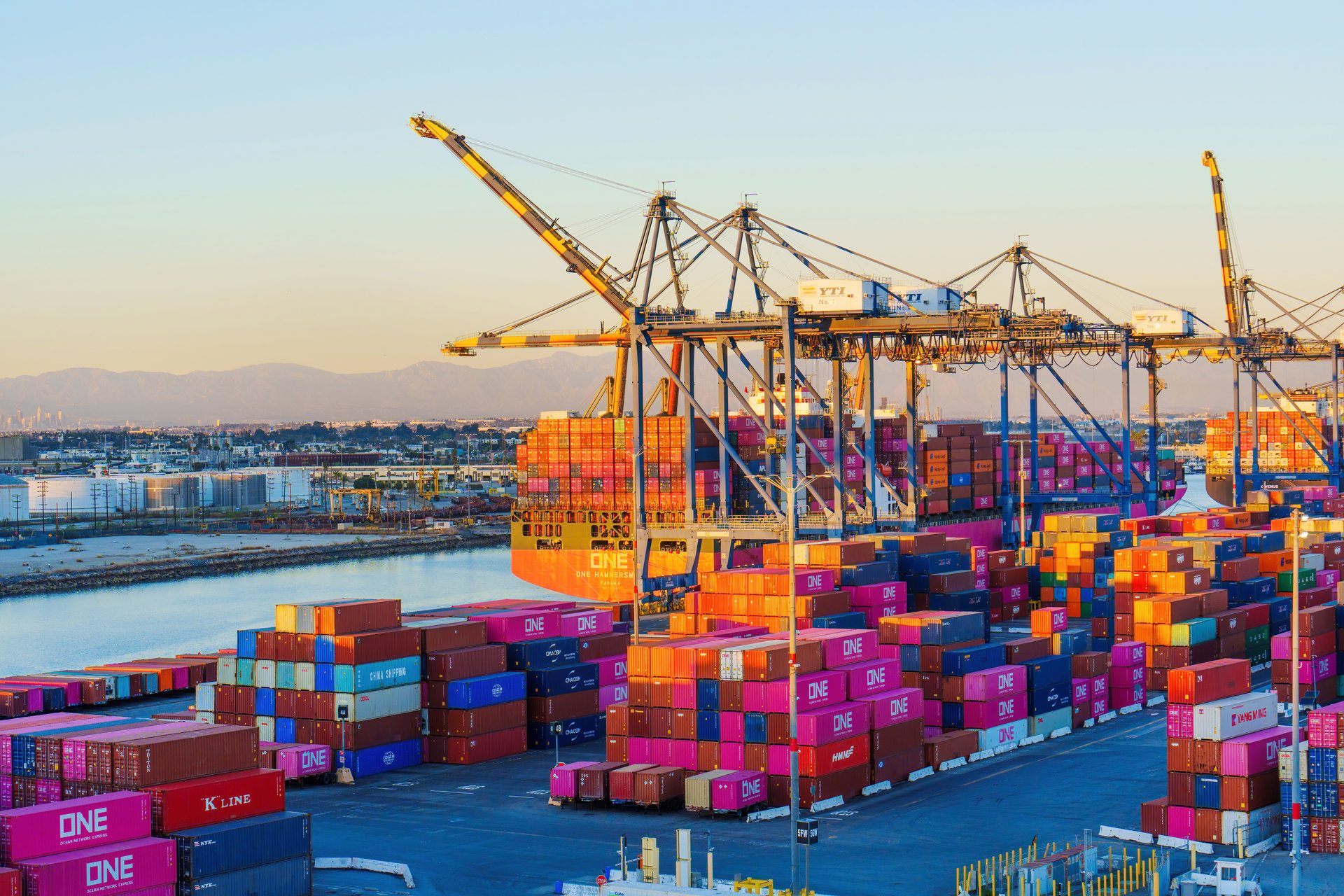 Container cranes working a vessel at a commercial port at dusk