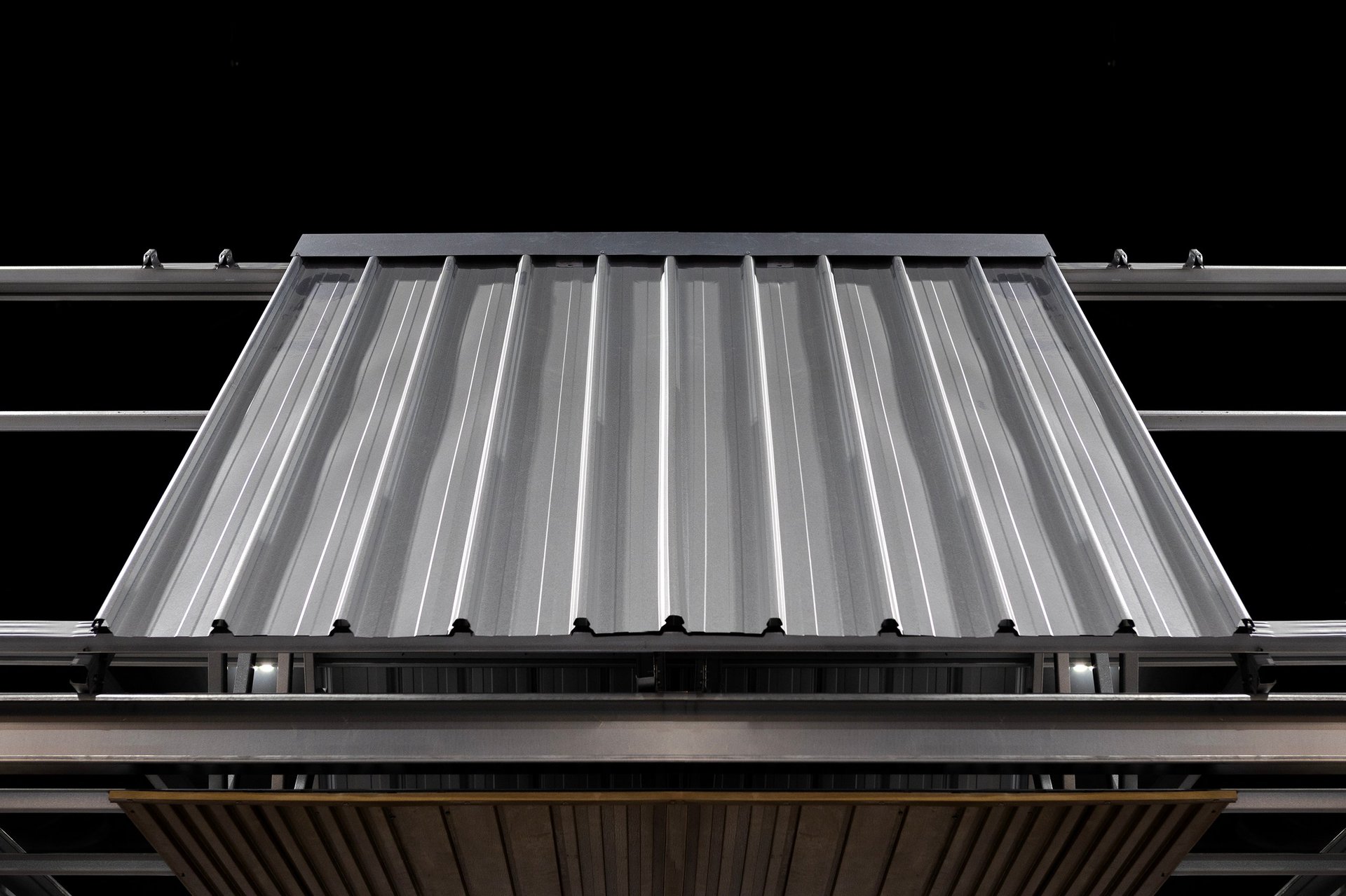 Profiled galvanized roof sheeting being laid onto a steel roof beam during construction