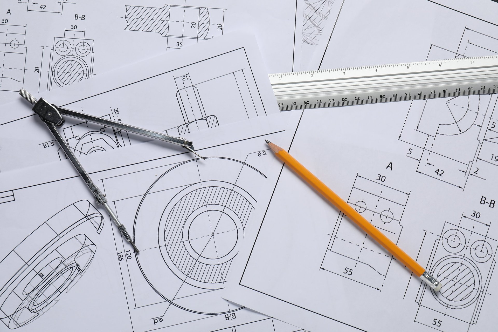 Engineering drawings, a pencil, a ruler and a divider laid out on a table, representing the schedule and detailing documents that a bar enquiry has to reference.