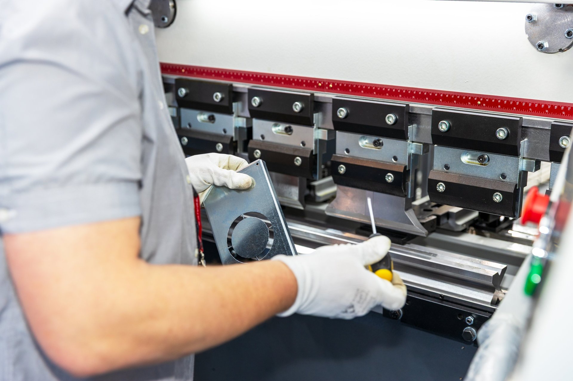 Operator forming a steel sheet component on a CNC press brake in a fabrication workshop