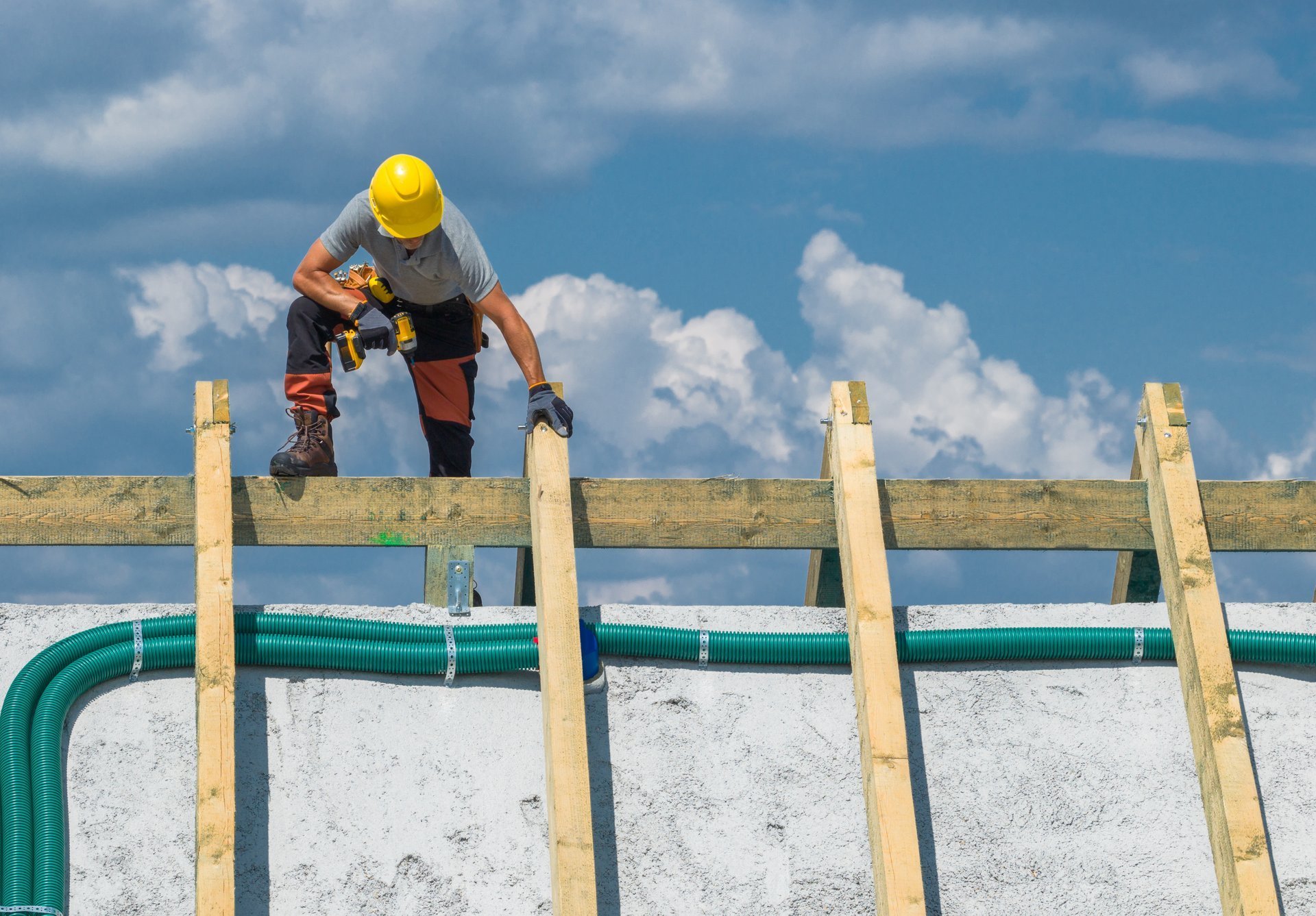 Construction worker carrying beams while standing on scaffolding at a building site