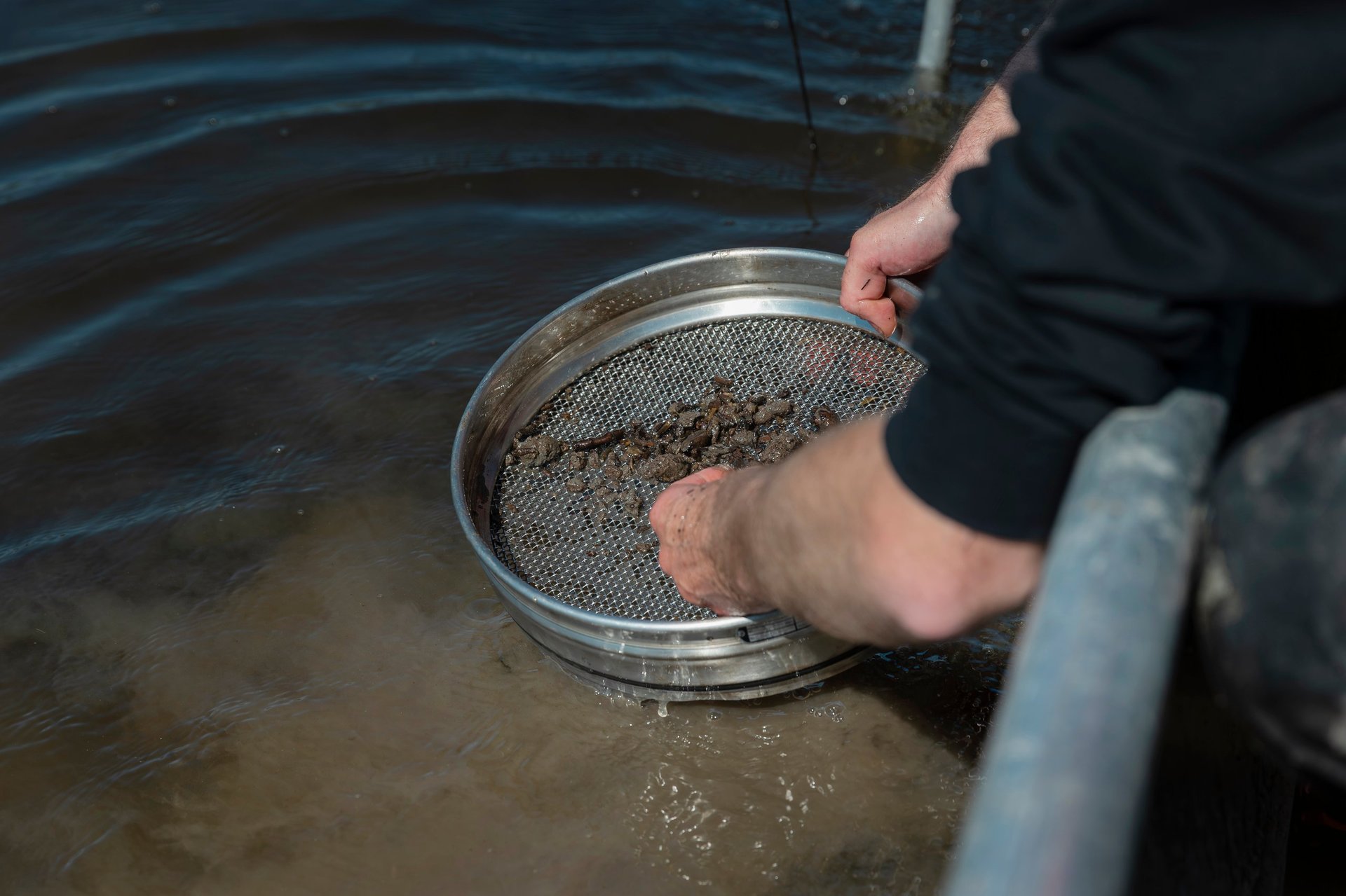 Material being passed through a test sieve during sample preparation work.