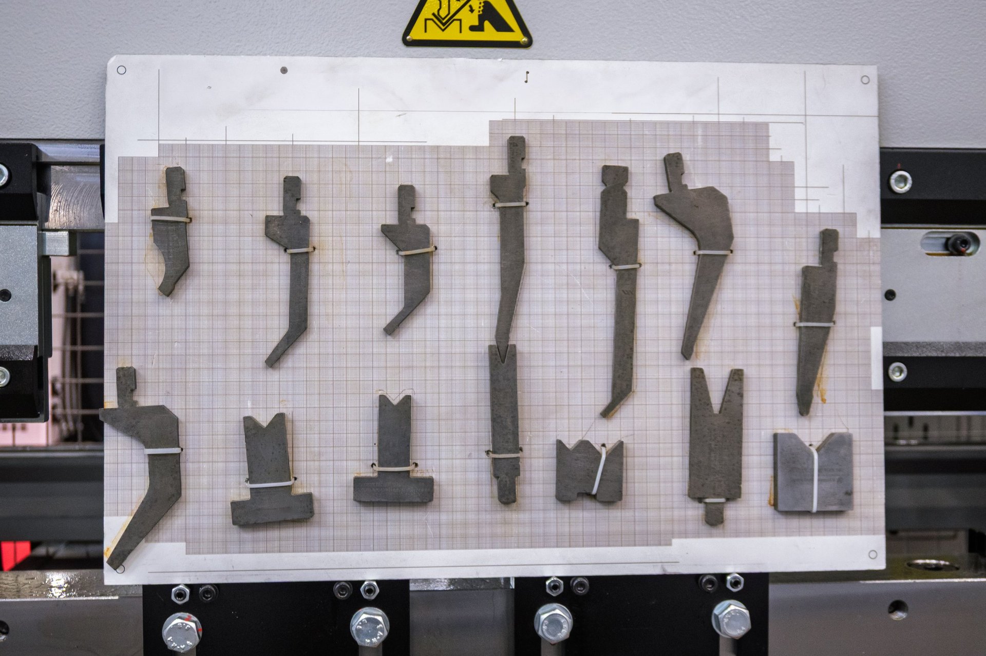 Press brake tooling and dies arranged on a storage board in a fabrication shop