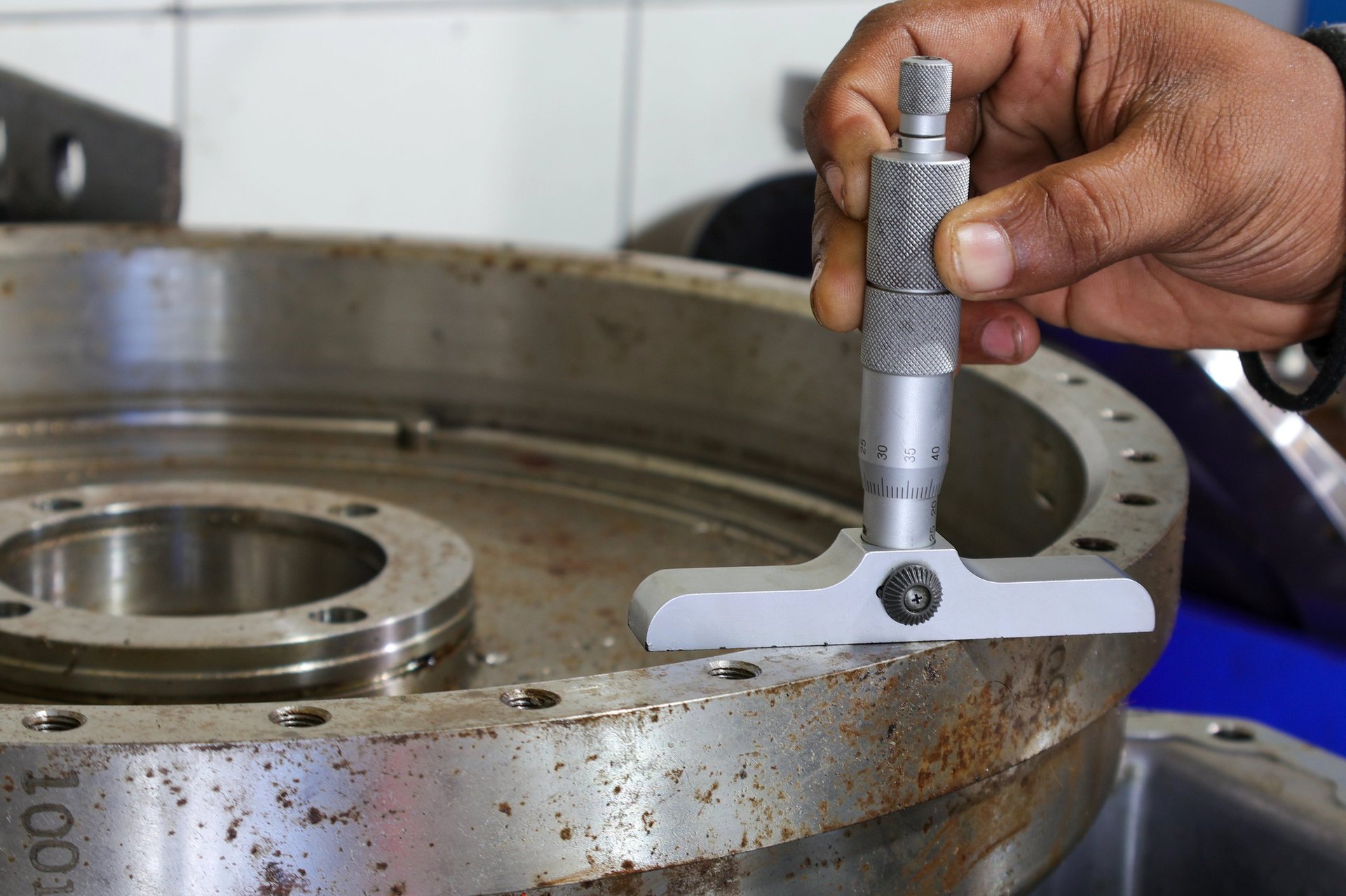 Depth micrometer being used to verify the thickness of an industrial metal component