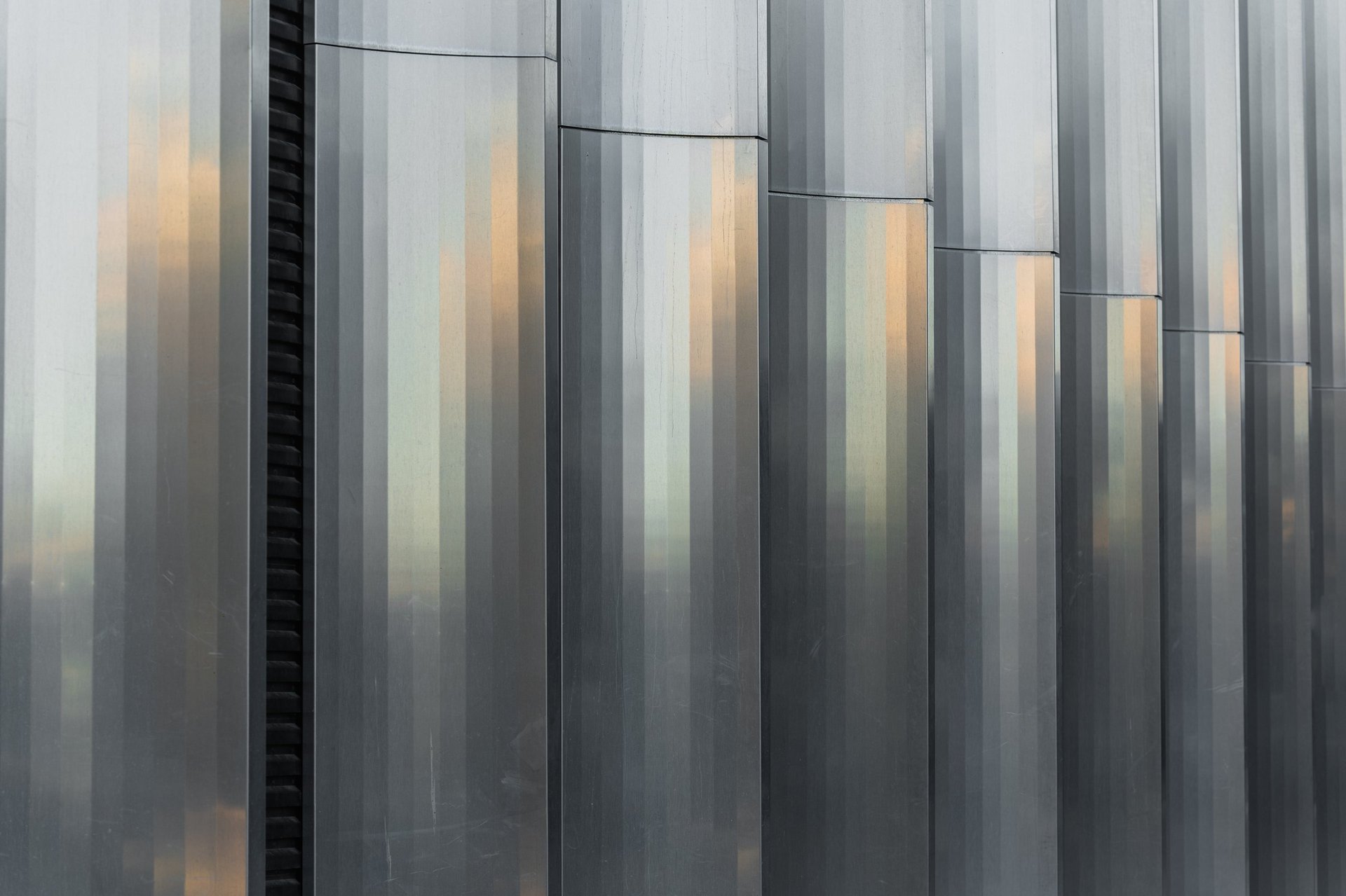Vertically profiled corrugated metal cladding panels forming a building envelope