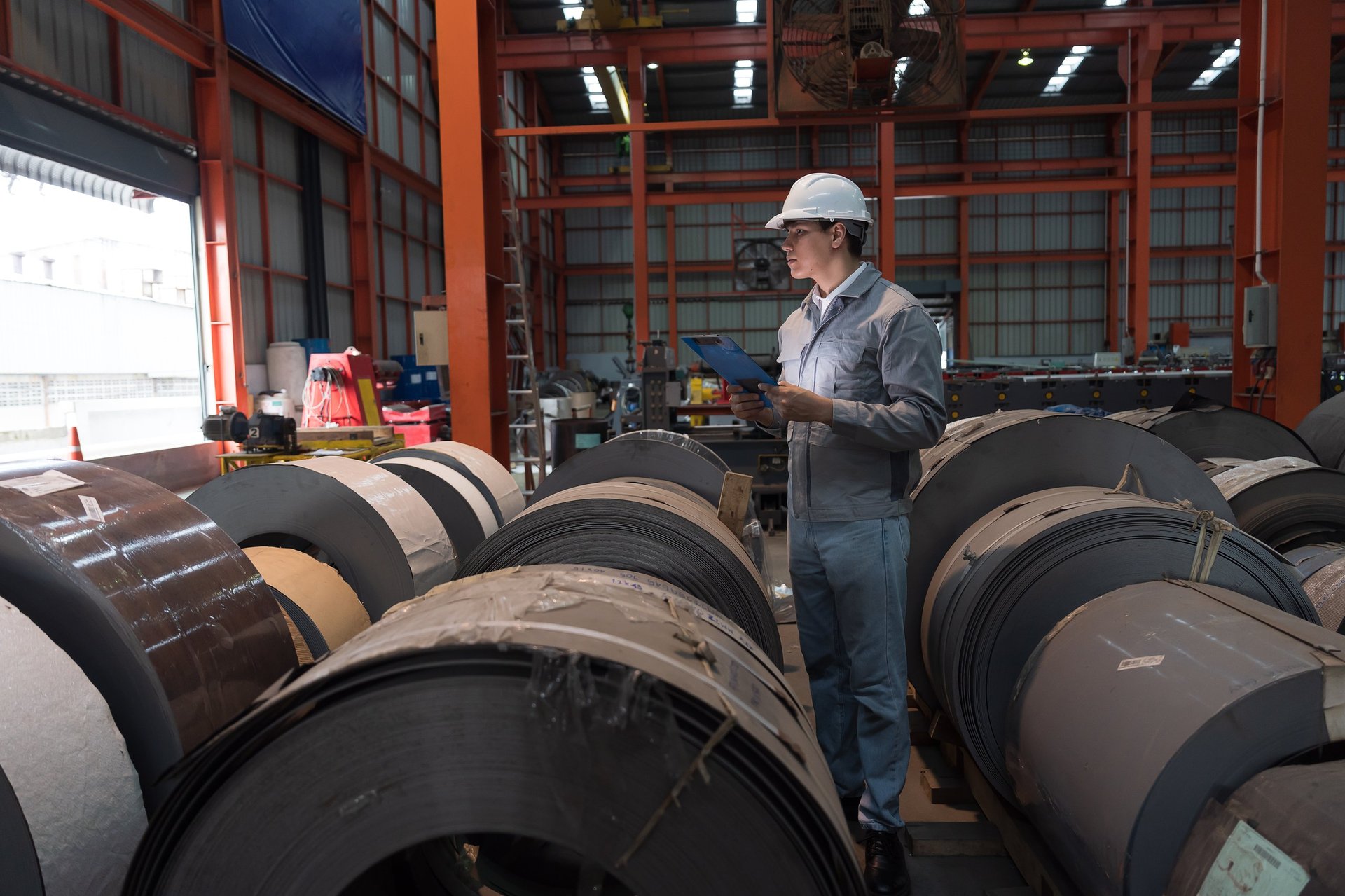 Factory worker inspecting a hot rolled steel coil during quality checks