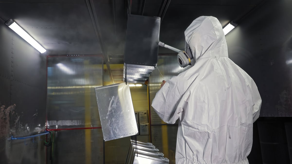 Operator applying a coating to prepared metal parts — the downstream step the sheet's surface feeds into