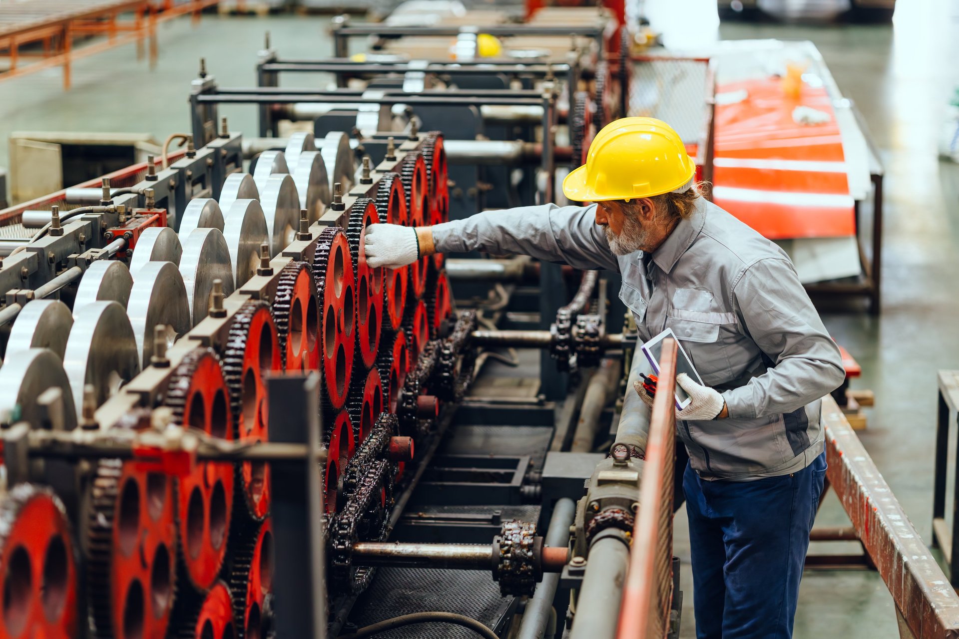 Technician checking steel tube plant machinery during a procurement inspection