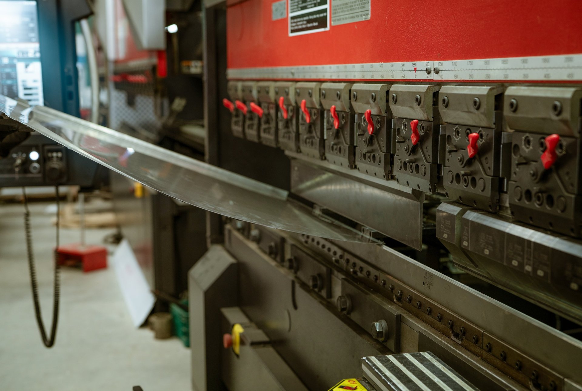 CNC press brake forming a folded metal enclosure panel in a fabrication workshop