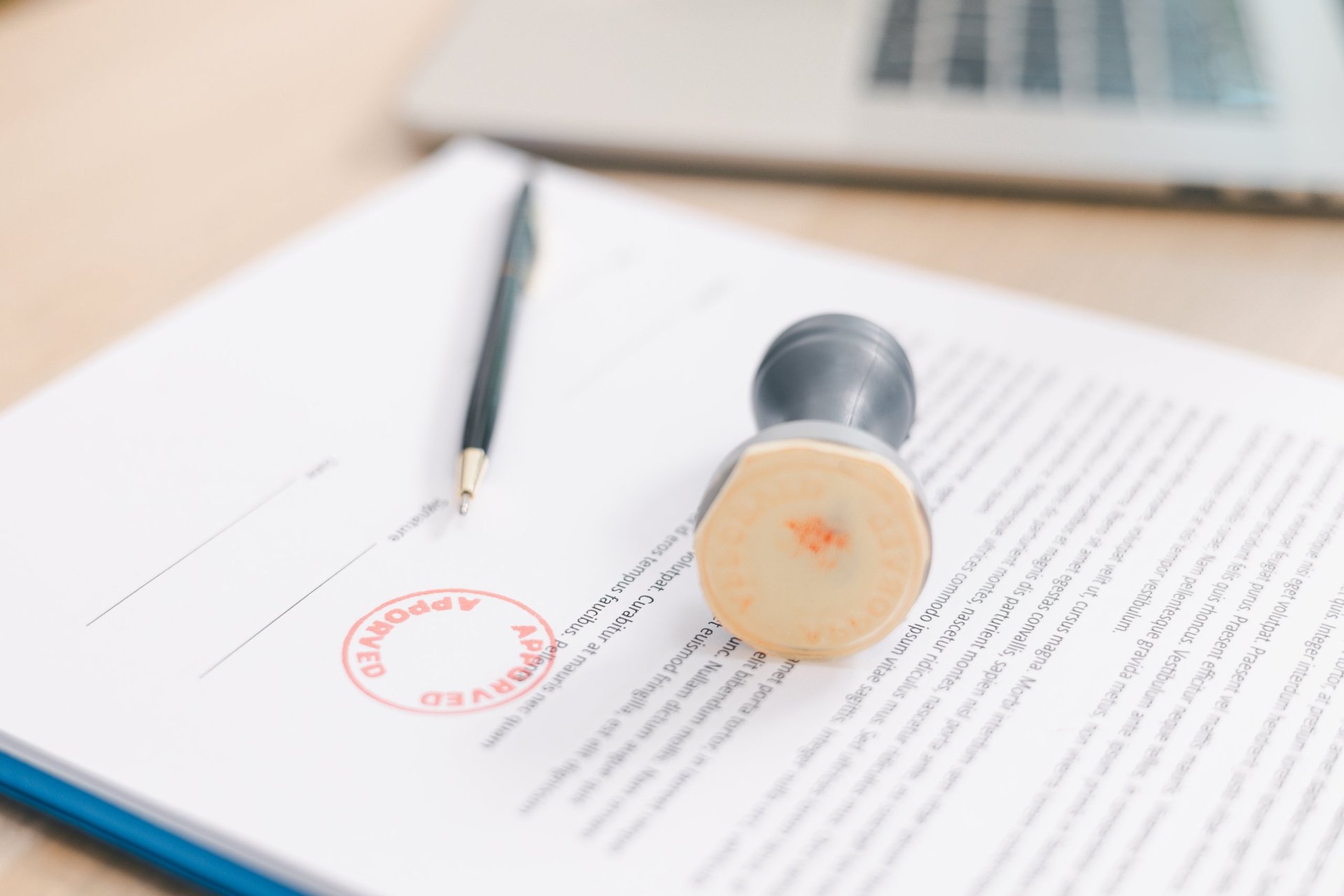 Approved stamp applied to a signed document on a desk, illustrating the certificate and approval records against which a delivered consignment is checked.