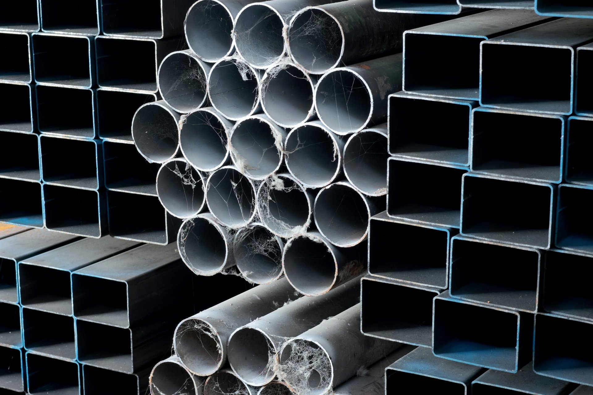 Stacked square hollow section profiles and steel pipes in an industrial metal warehouse