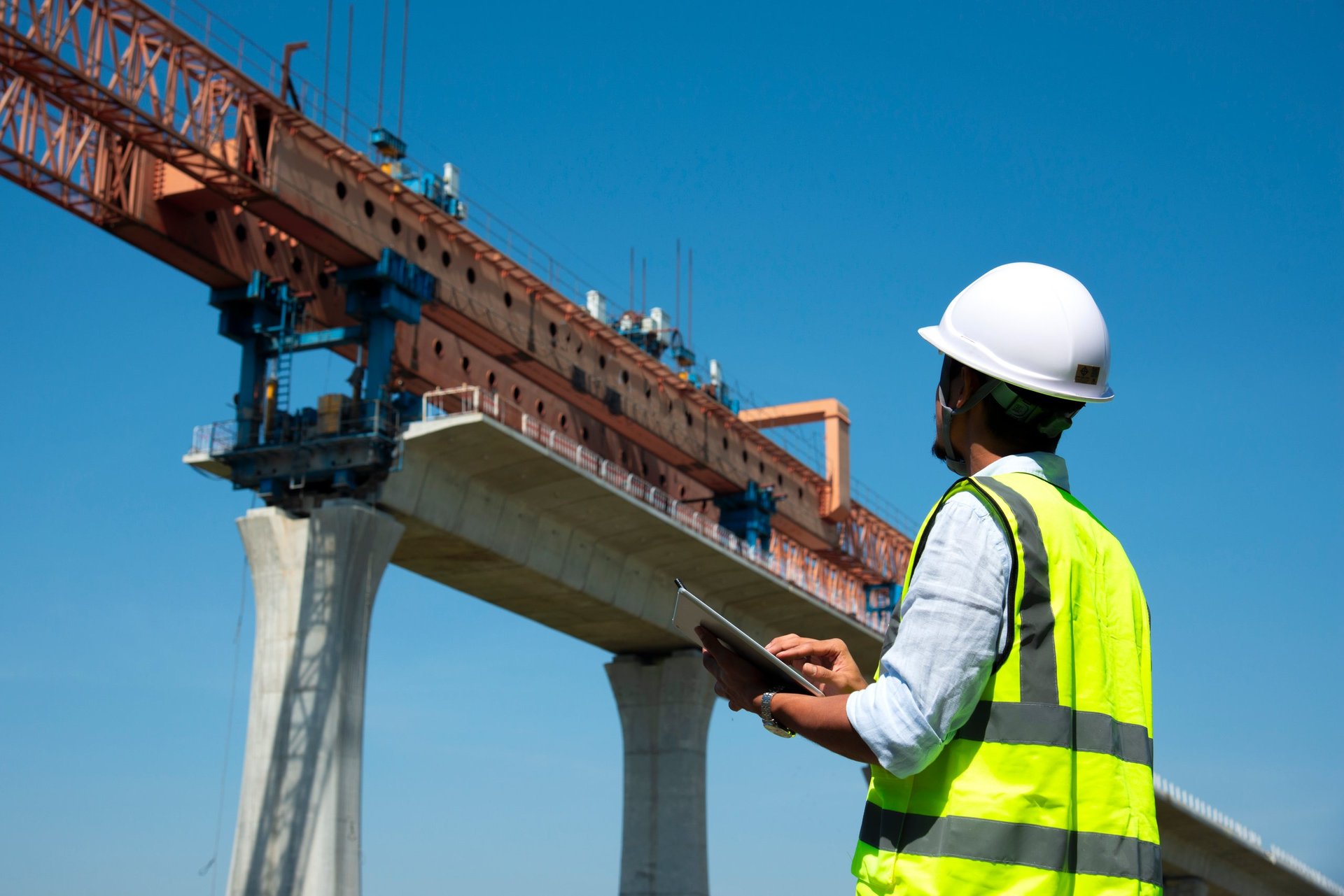 Engineers using survey equipment and drawings on an infrastructure project, illustrating the design-side review that governs permitted use of a specified grade.