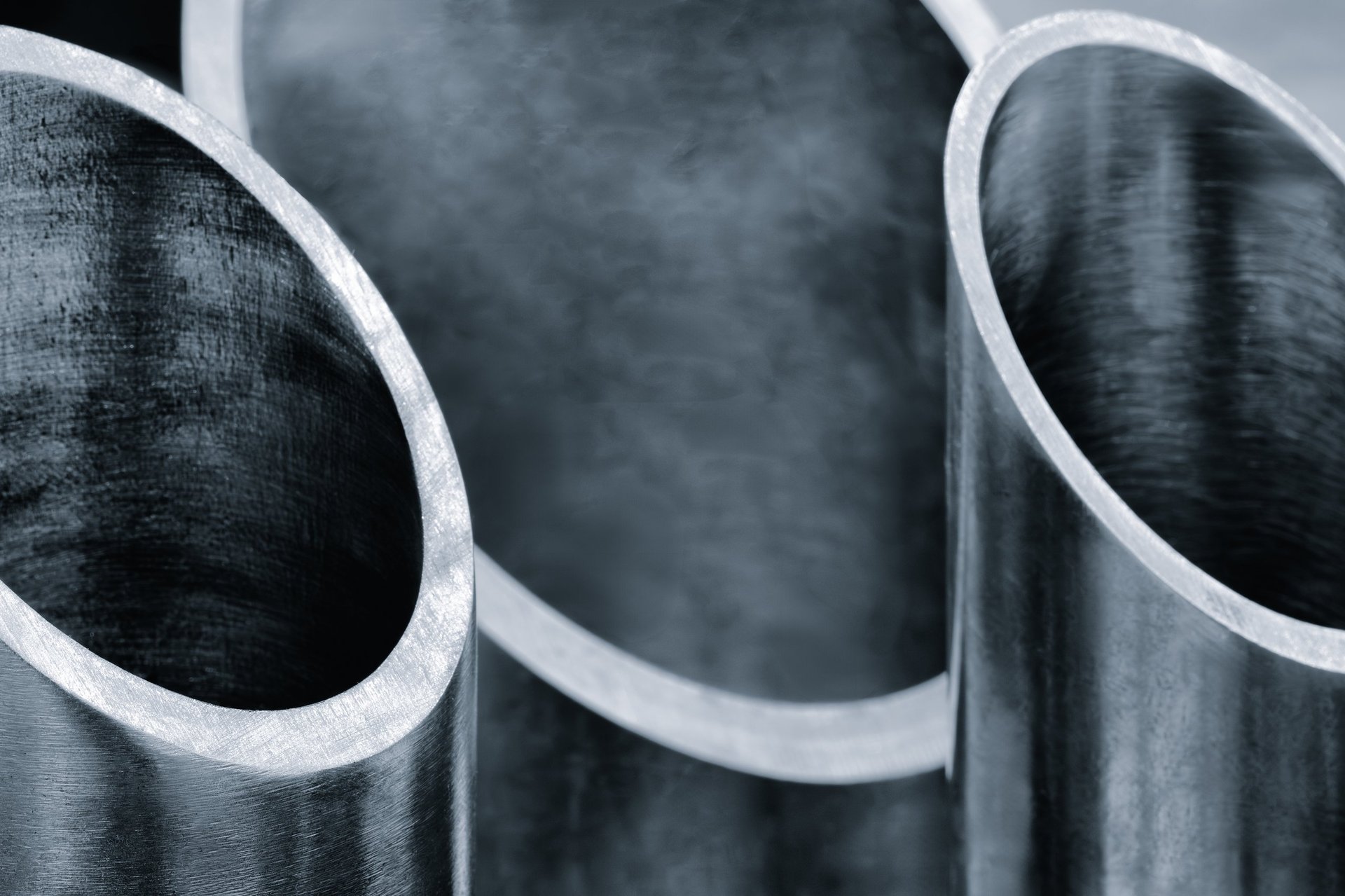 Circular steel tubes being cut to length on an industrial saw, showing the curved cut ends