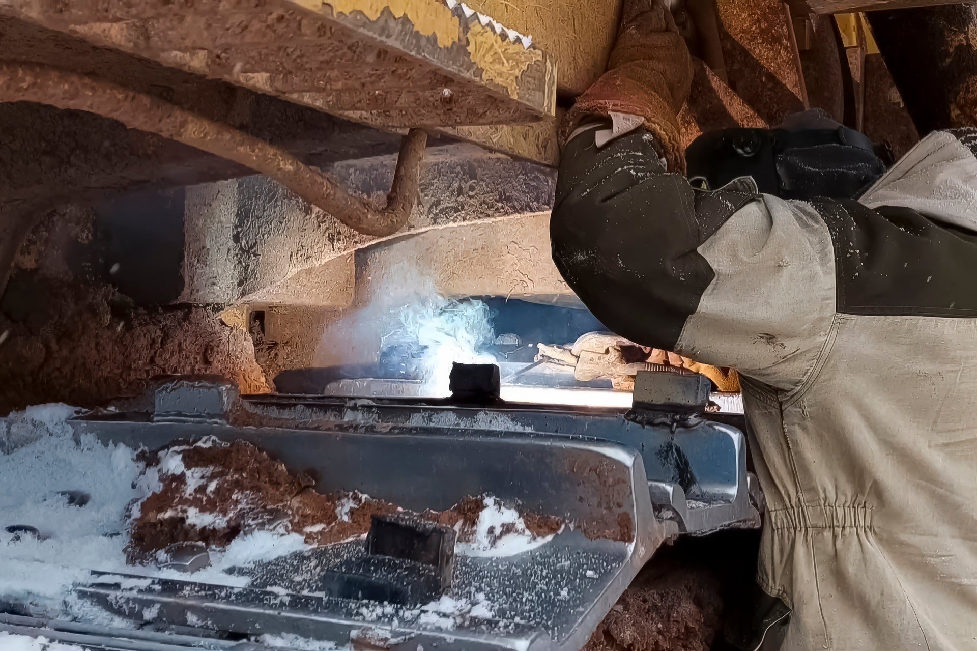 Fabricator welding a steel member in an industrial workshop