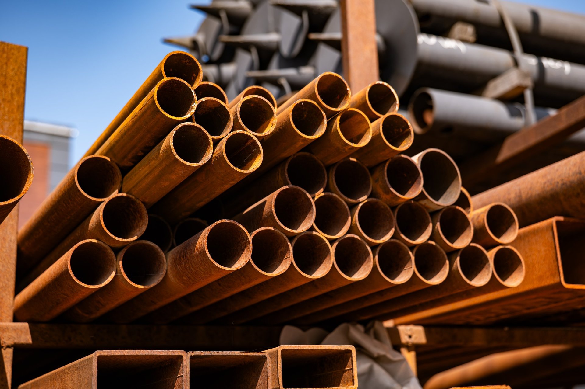 Steel sections and pipes stacked in an open storage area