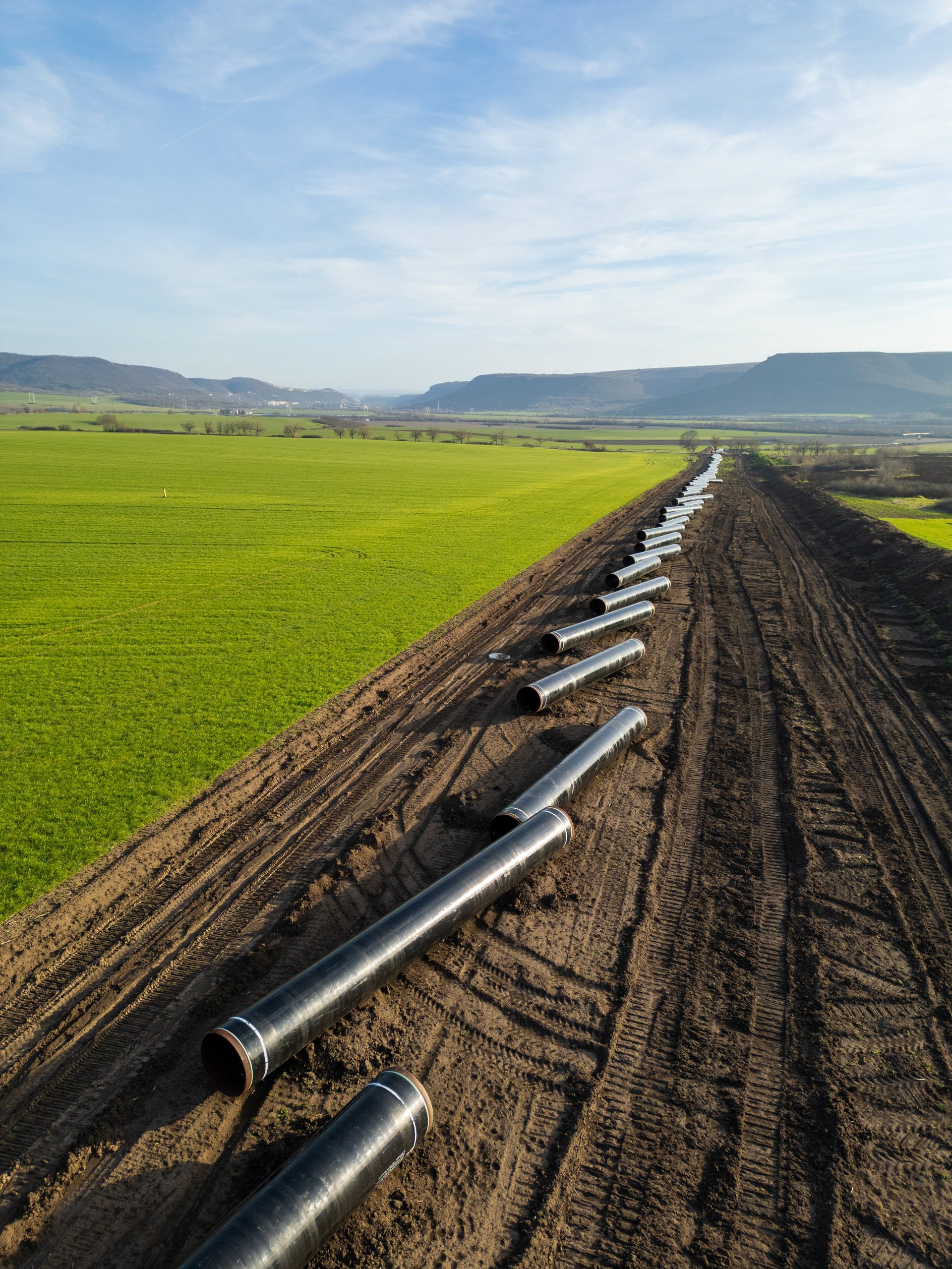 Workers and machinery installing large steel pipes for a gas pipeline project
