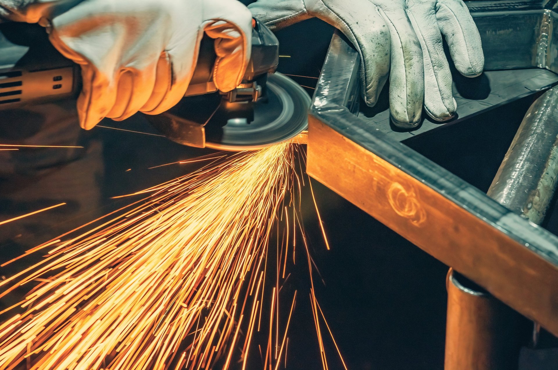 Sparks from metalwork in a dark fabrication workshop during a welding or grinding operation