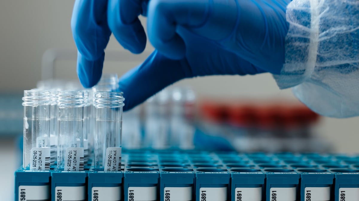 A laboratory technician organising labelled sample vials in a rack during sample division.