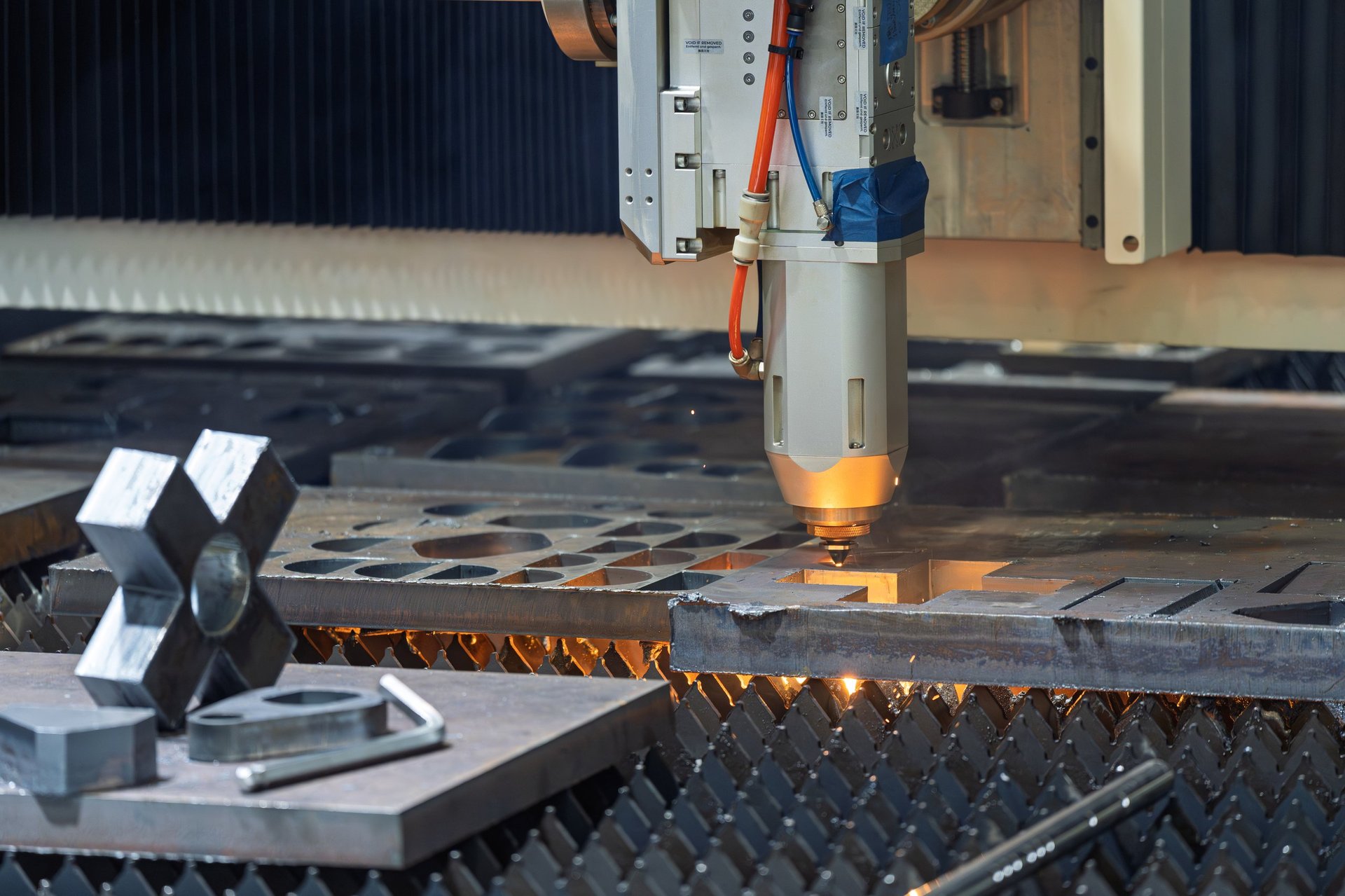 Industrial laser cutting machine profiling a steel sheet in a fabrication workshop