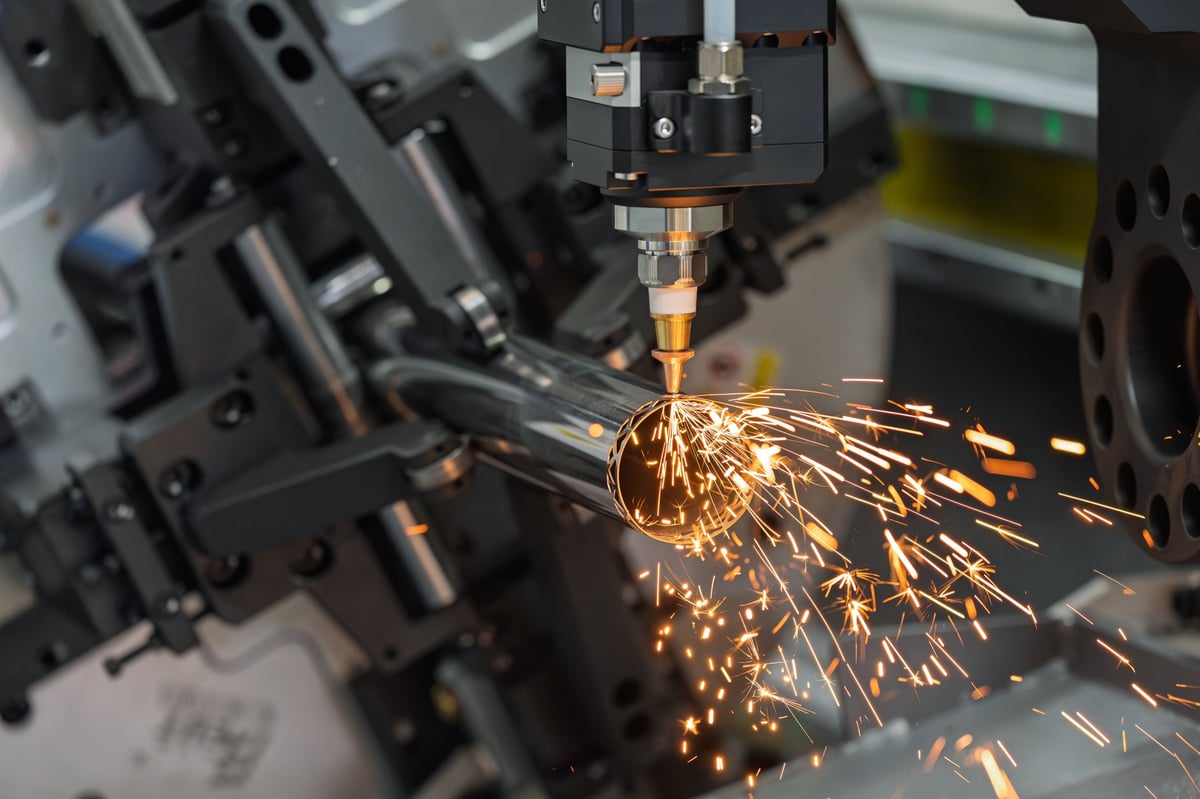 Machine cutting steel tube in an industrial fabrication workshop