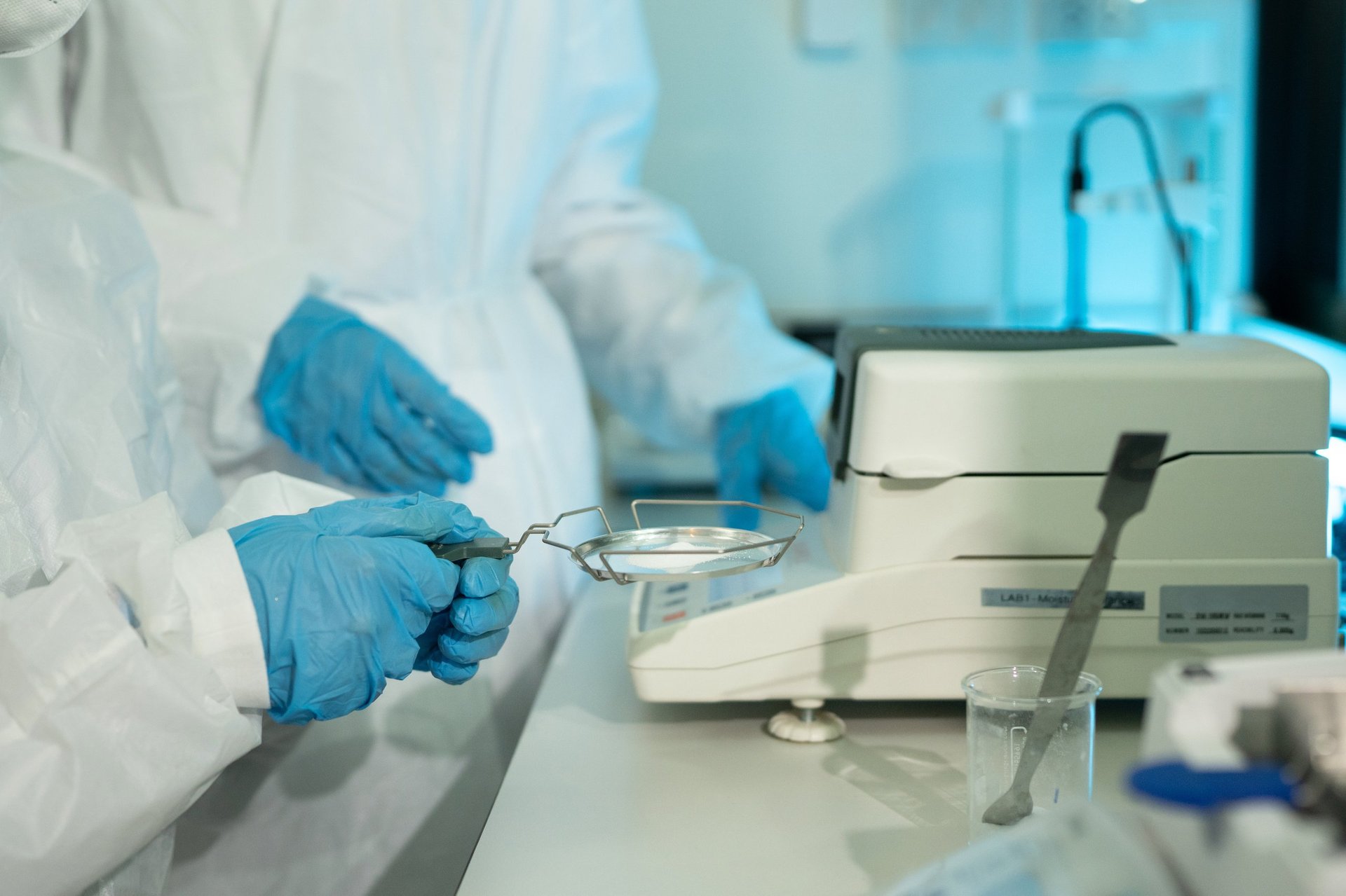 Two laboratory technicians working at an analytical balance during a chemical analysis.