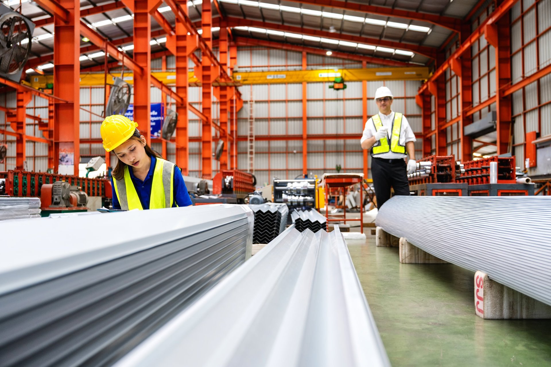 Technician inspecting steel sheet surfaces during quality control in a workshop