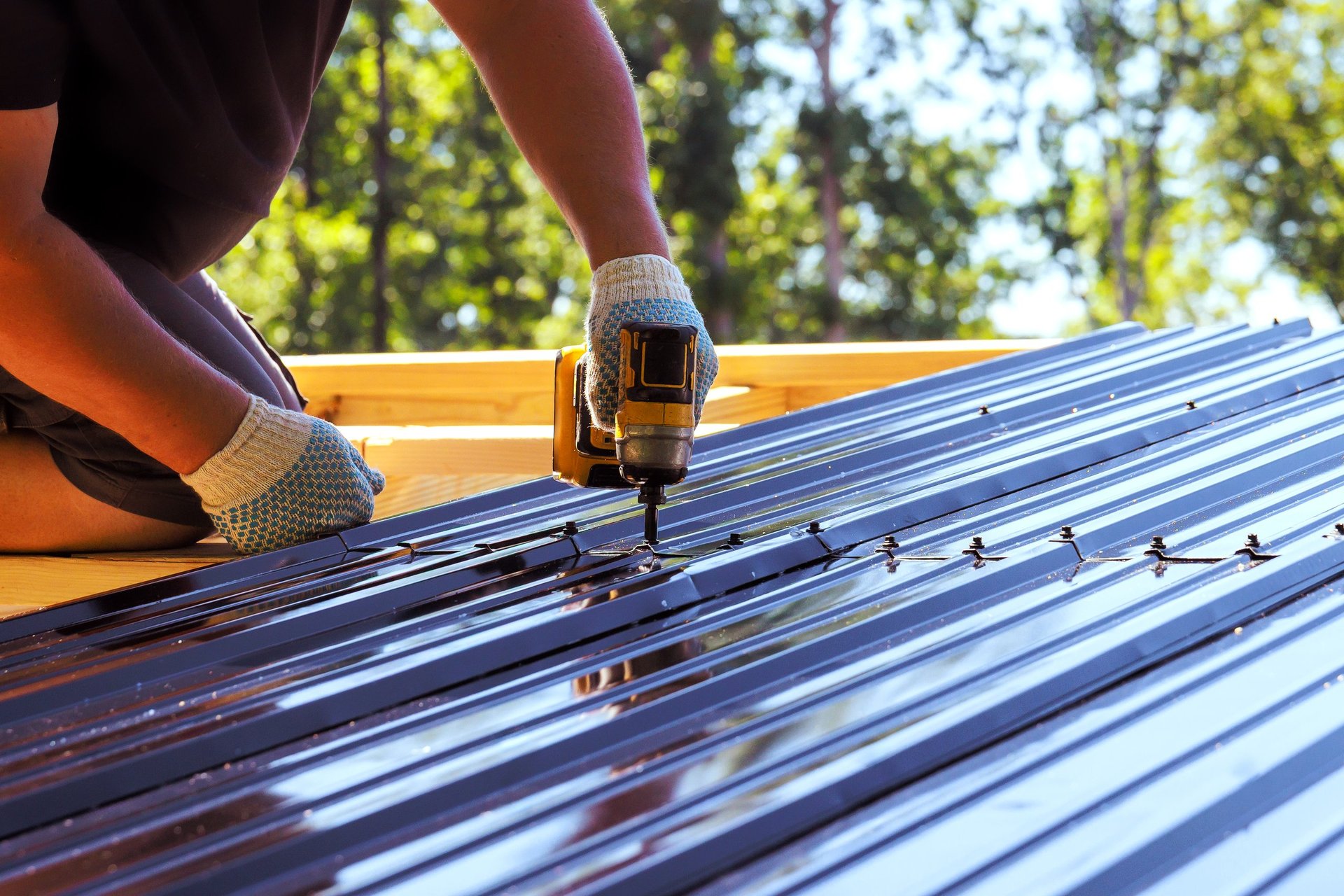 Contractor fixing profiled metal cladding panels onto a building frame at a construction site