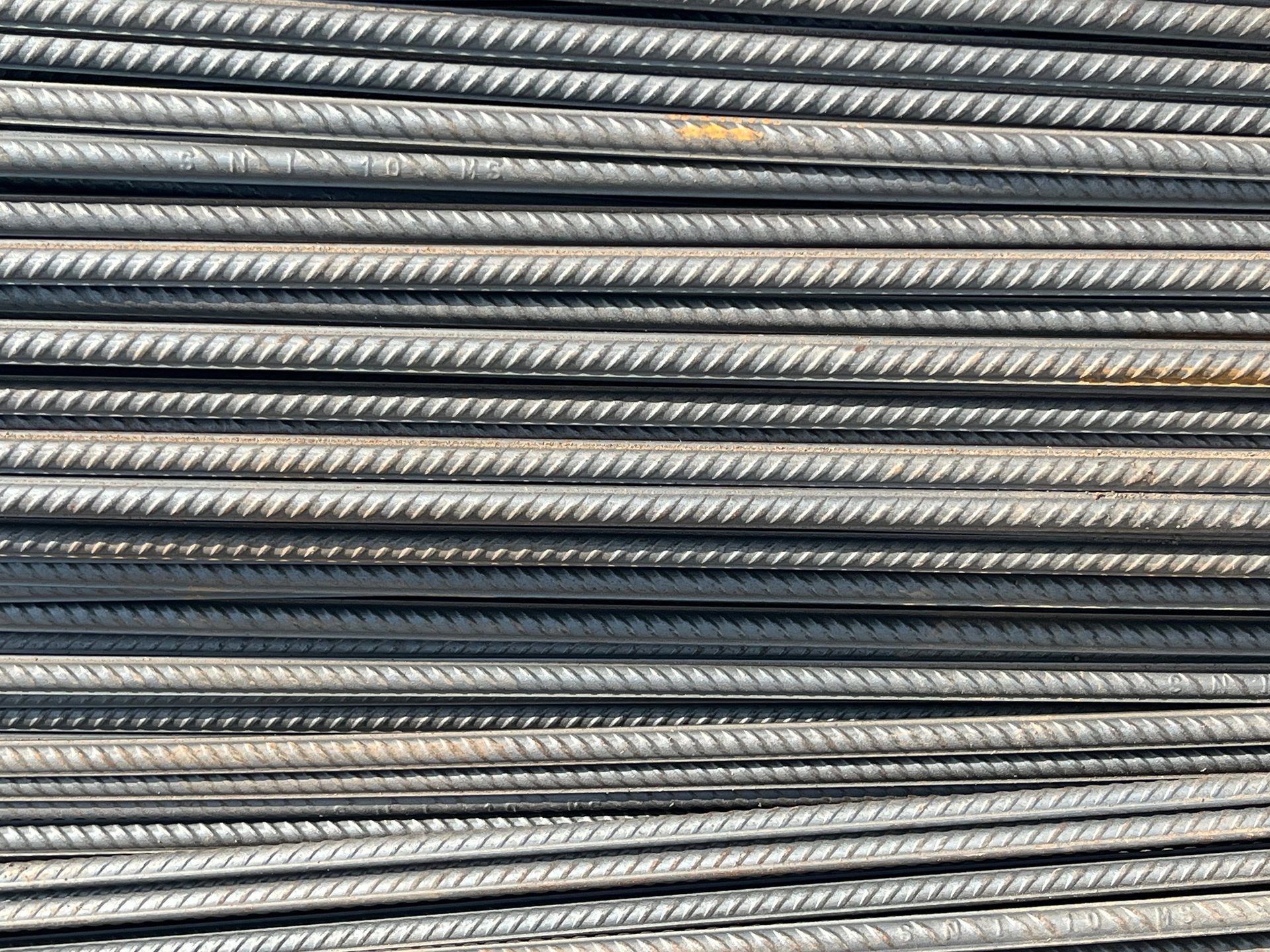 Bundled steel rebar and structural sections stacked at a UAE supply stockyard awaiting dispatch