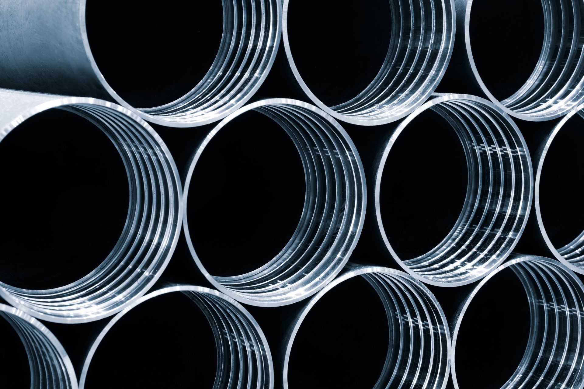 Stacked circular steel tubes with visible hollow ends in an industrial store
