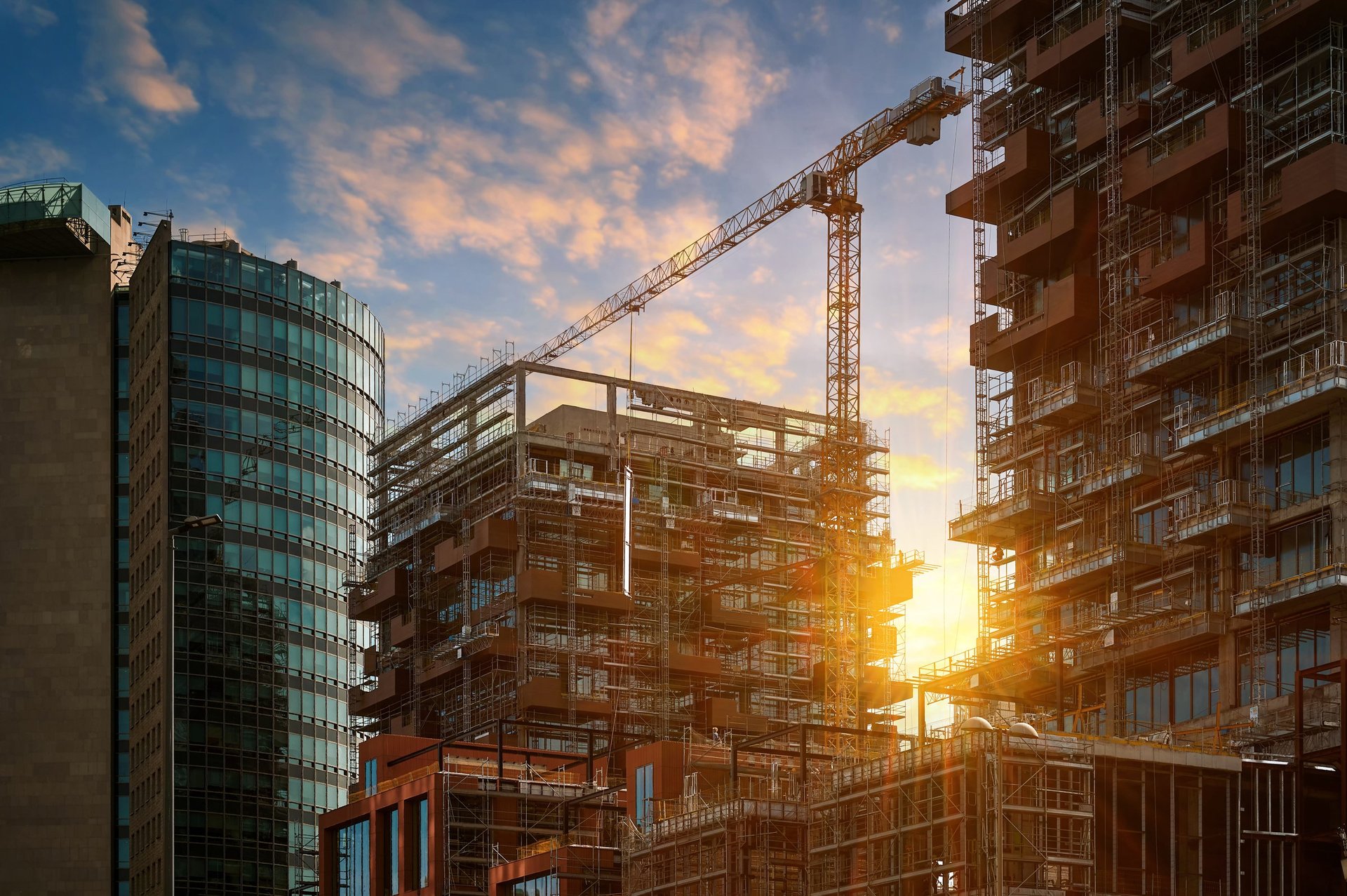Steel-framed building under construction with tower cranes above the structure
