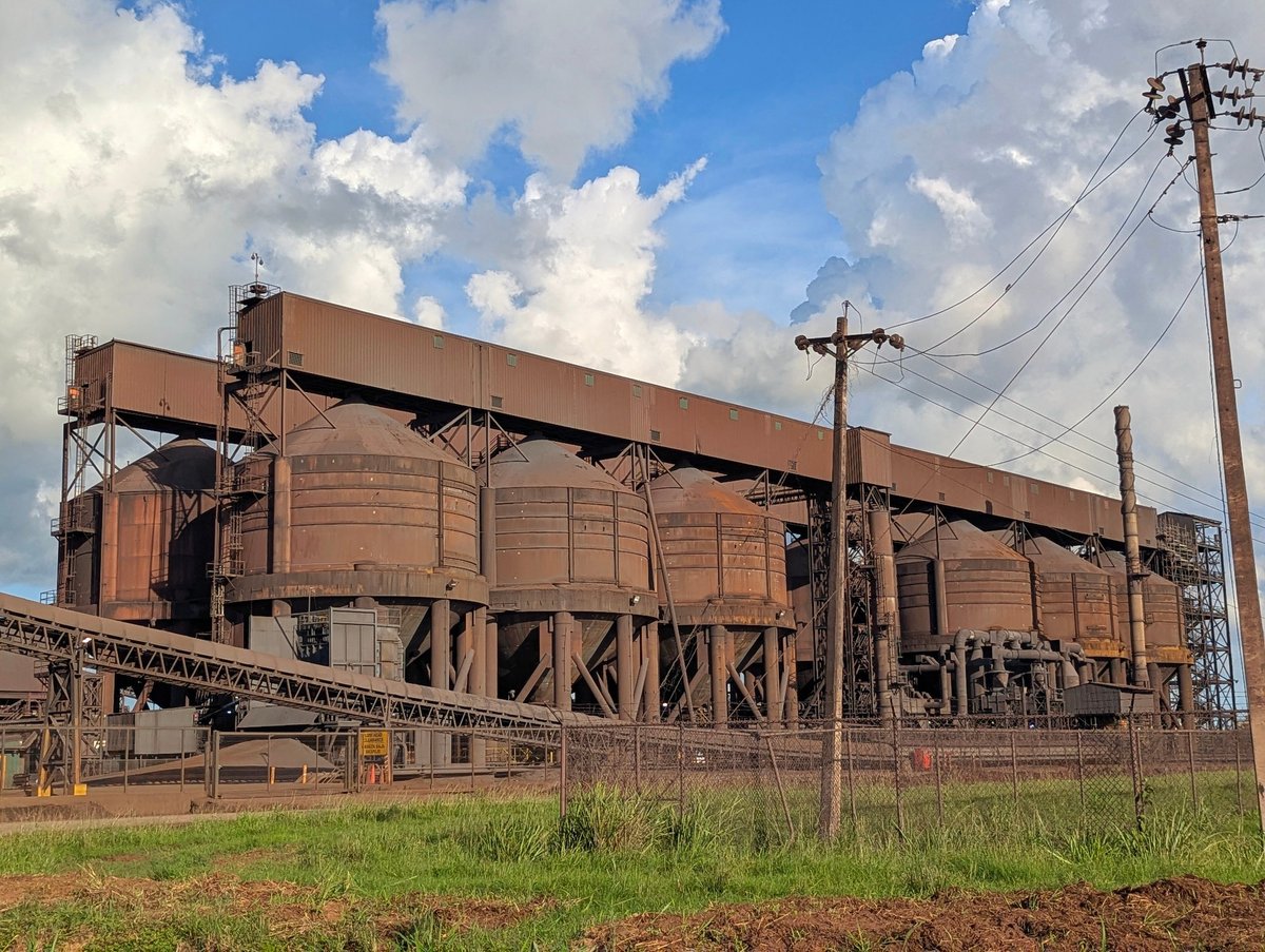 Large cylindrical raw-material processing vessels at an industrial steel plant site.
