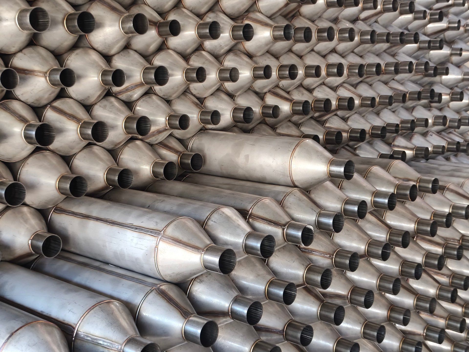 Rows of bright stainless steel pipes stacked in an industrial manufacturing warehouse