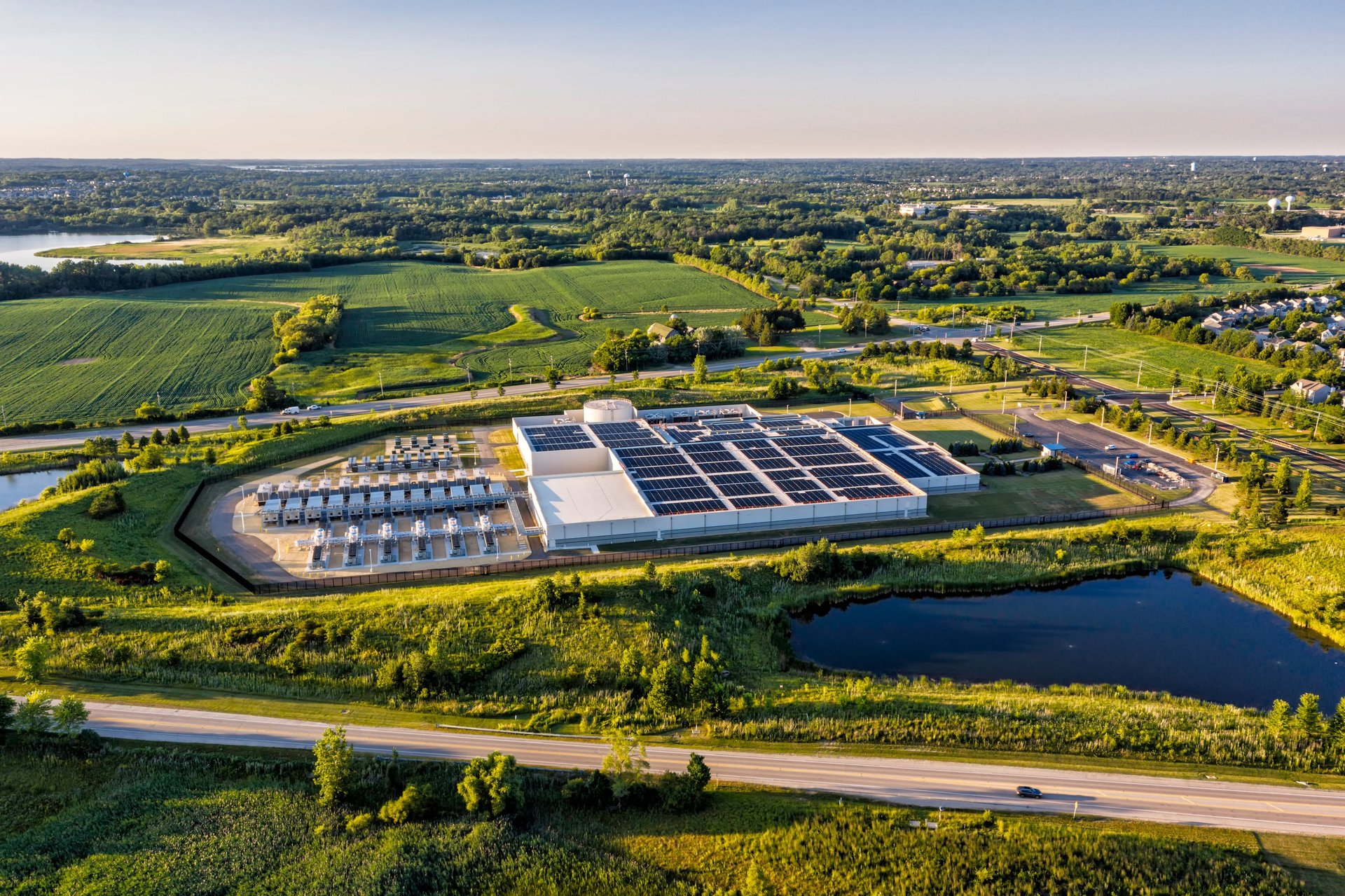 Aerial view of a large infrastructure site with a road and surrounding landscape