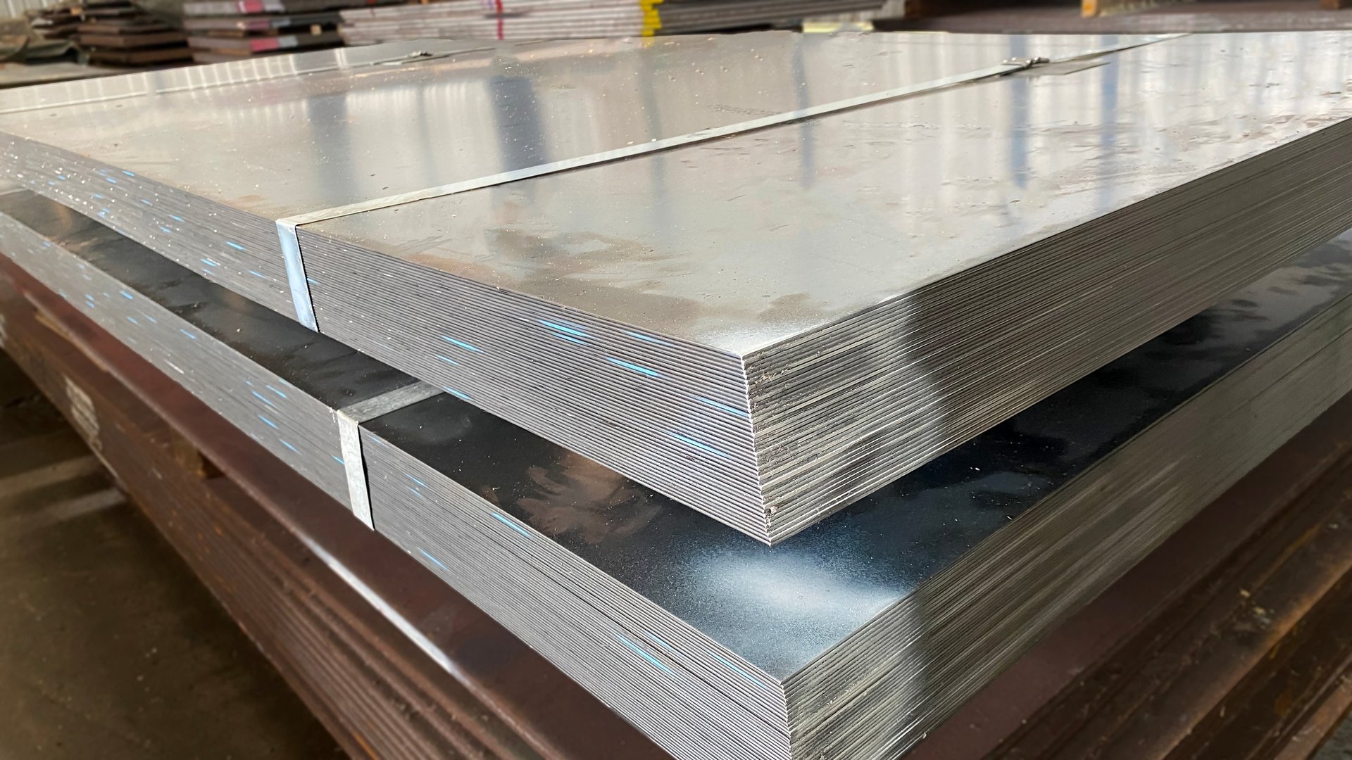 Stacked hot-rolled steel sheets stored in an industrial warehouse