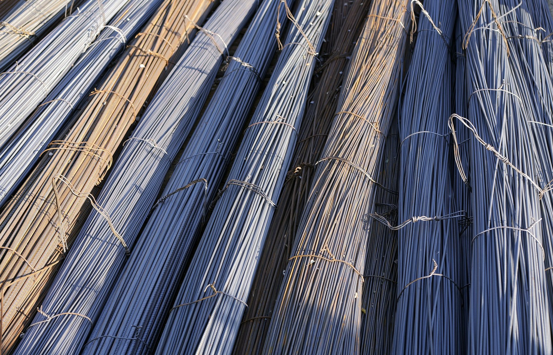 Bundles of steel rebar rods stacked closely together ready for use as concrete reinforcement, illustrating the bundle configuration a site lifting plan has to handle.