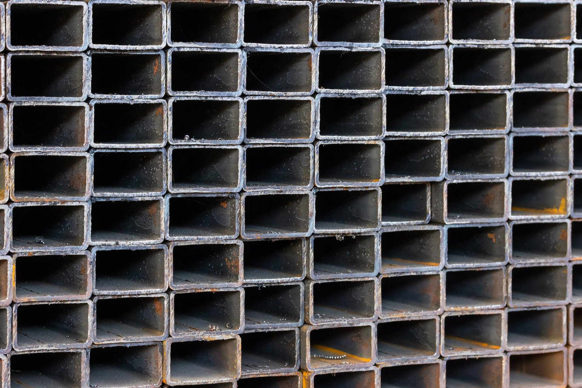 Stacked rectangular hollow steel sections and round tubes in tidy rows