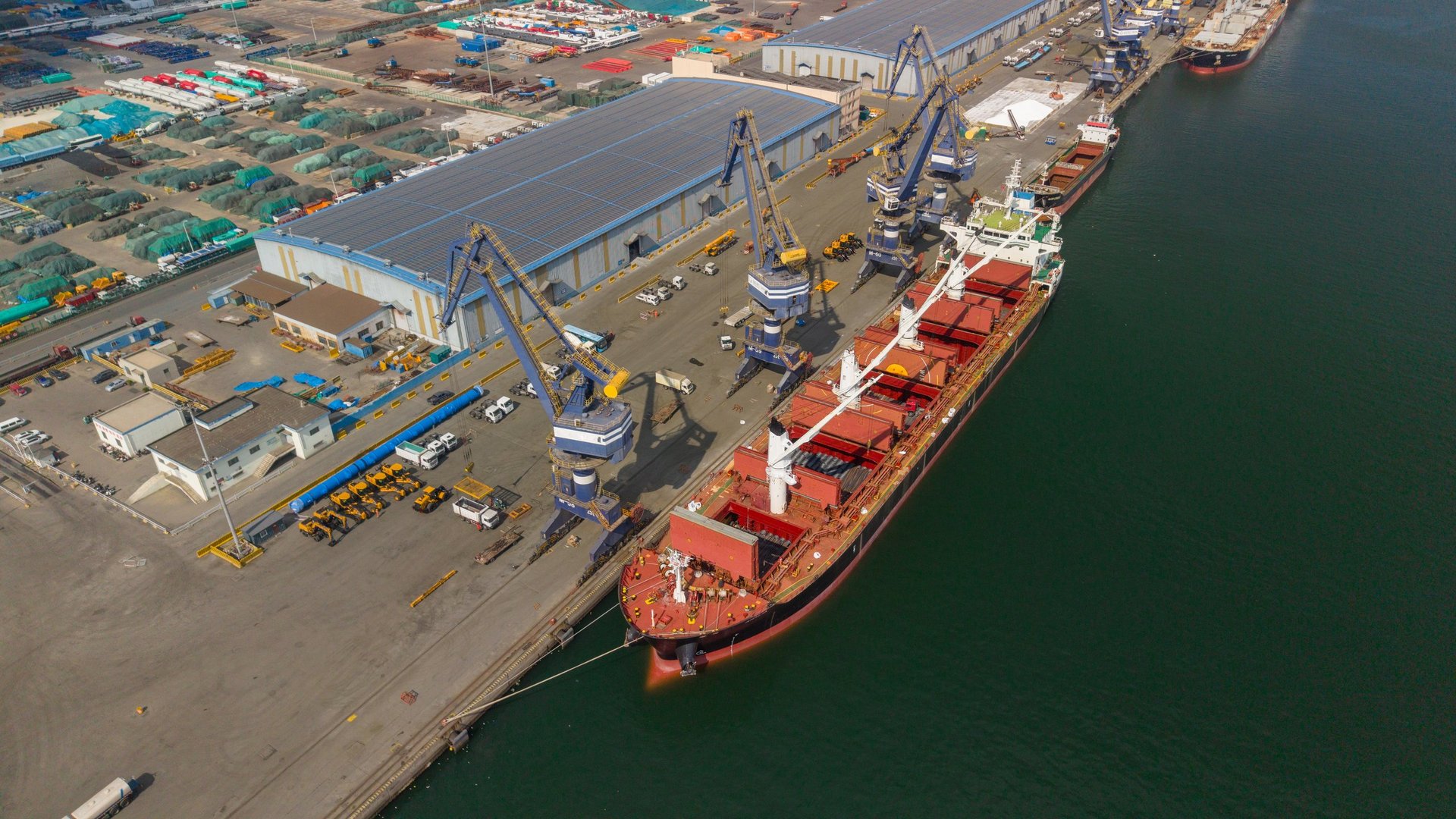 Aerial view of a commercial port terminal with bulk cargo handling equipment.